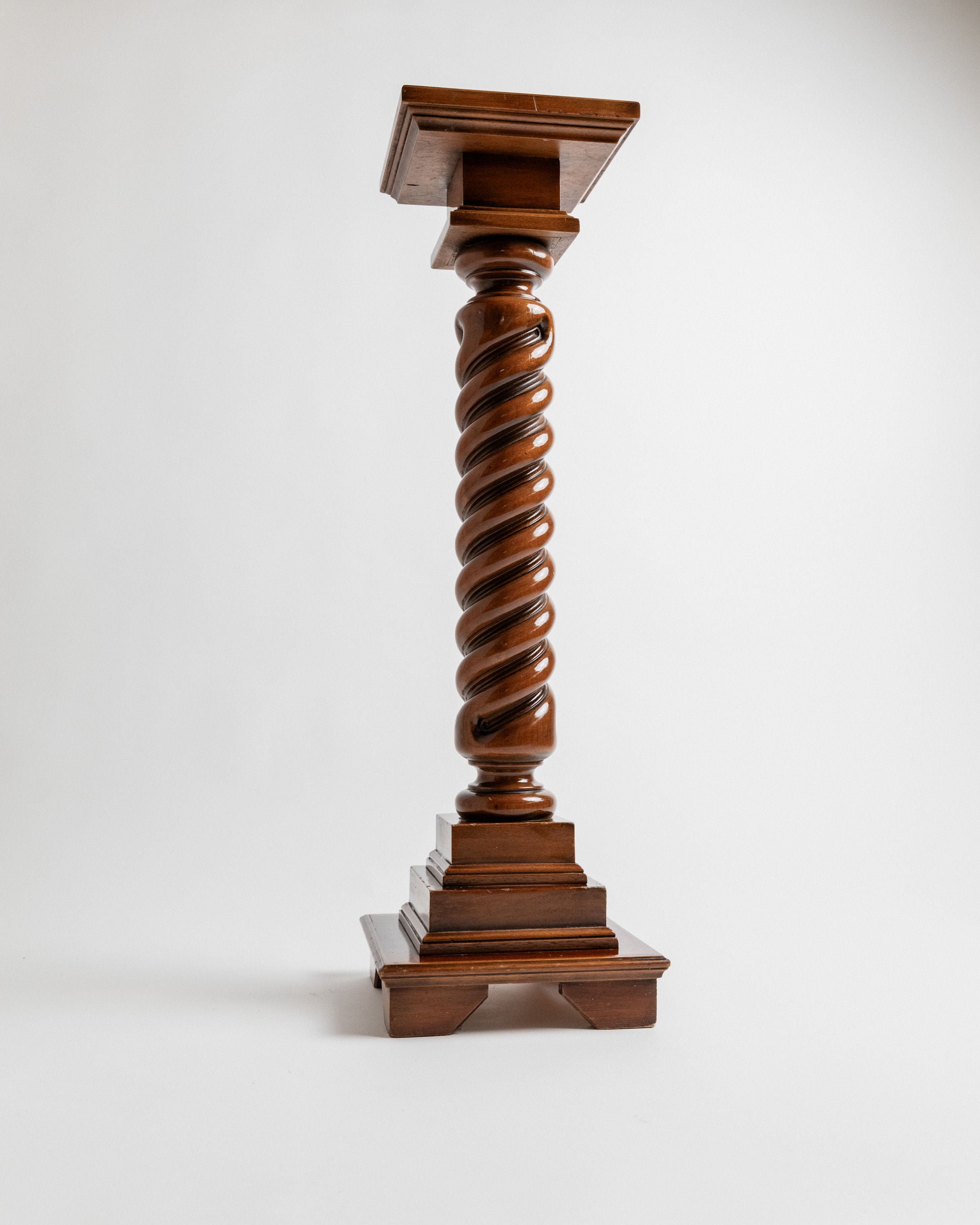 This Bottega Jacobs vintage wooden stand from Italy in the 1960s features a twisted column design with a square base. Its elegant dark solid wood finish beautifully highlights the spiral detail and craftsmanship, all set against a plain white background.