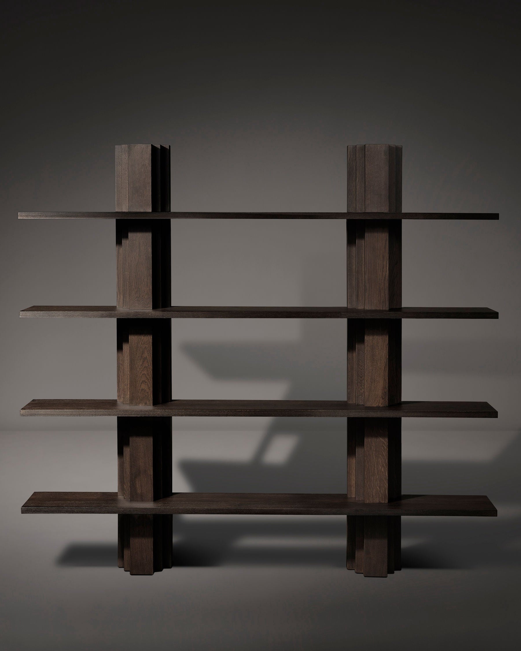 Explore Mokko's Brut Bibliothèque, a minimalist bookshelf made from solid European oak. Its grid design with five horizontal shelves and three vertical panels adds depth and character, casting a subtle shadow on dark-toned walls.