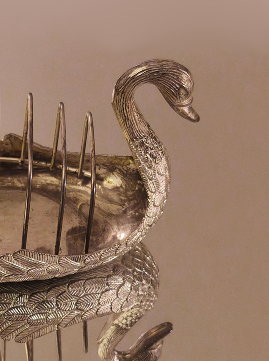 Introducing the Swan Toast Rack by Les Objoies, a vintage silver-plated toast holder designed in the shape of a swan. The elegantly curved neck and intricately detailed leaf patterns on the body make it a stunning breakfast table accessory. It features slots for holding toast, all beautifully reflected on its smooth, shiny surface.