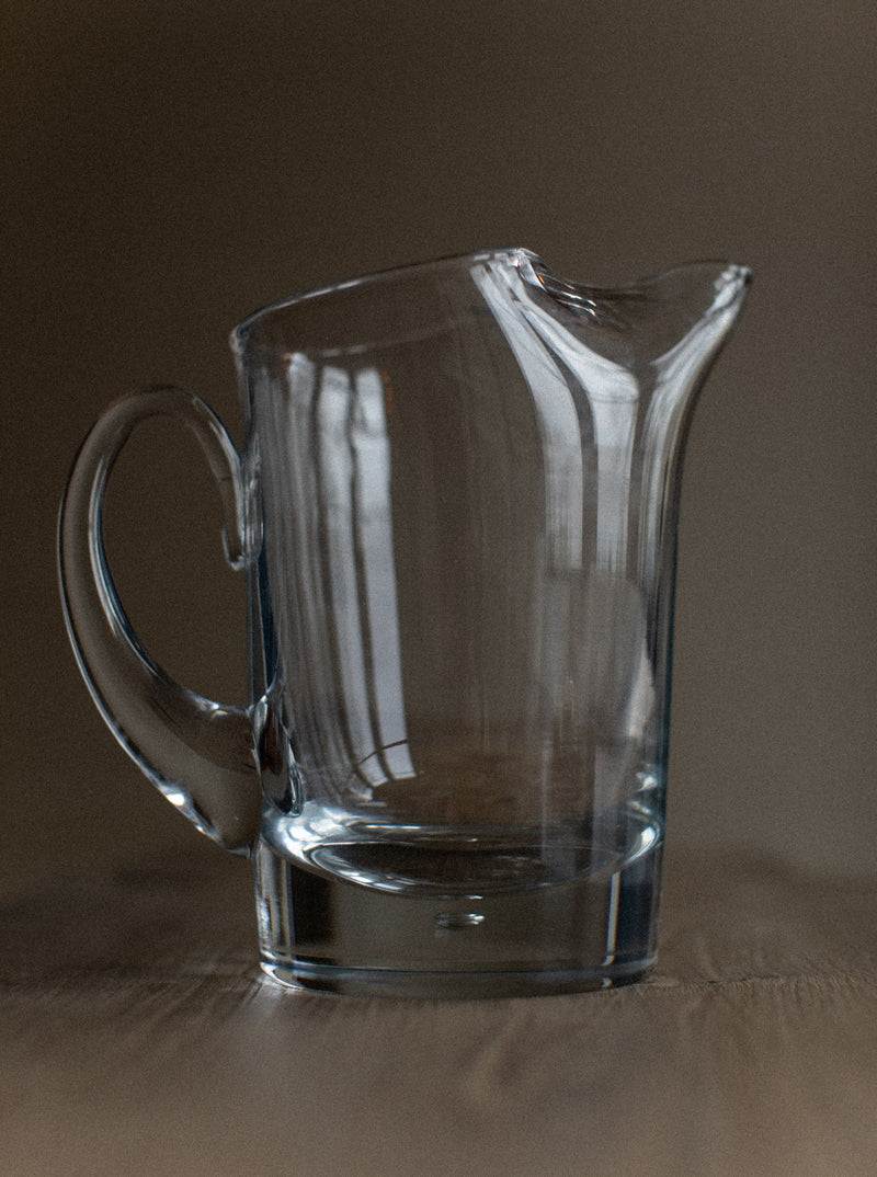 Glass pitcher with curved handle and lid, perfect for serving drinks
