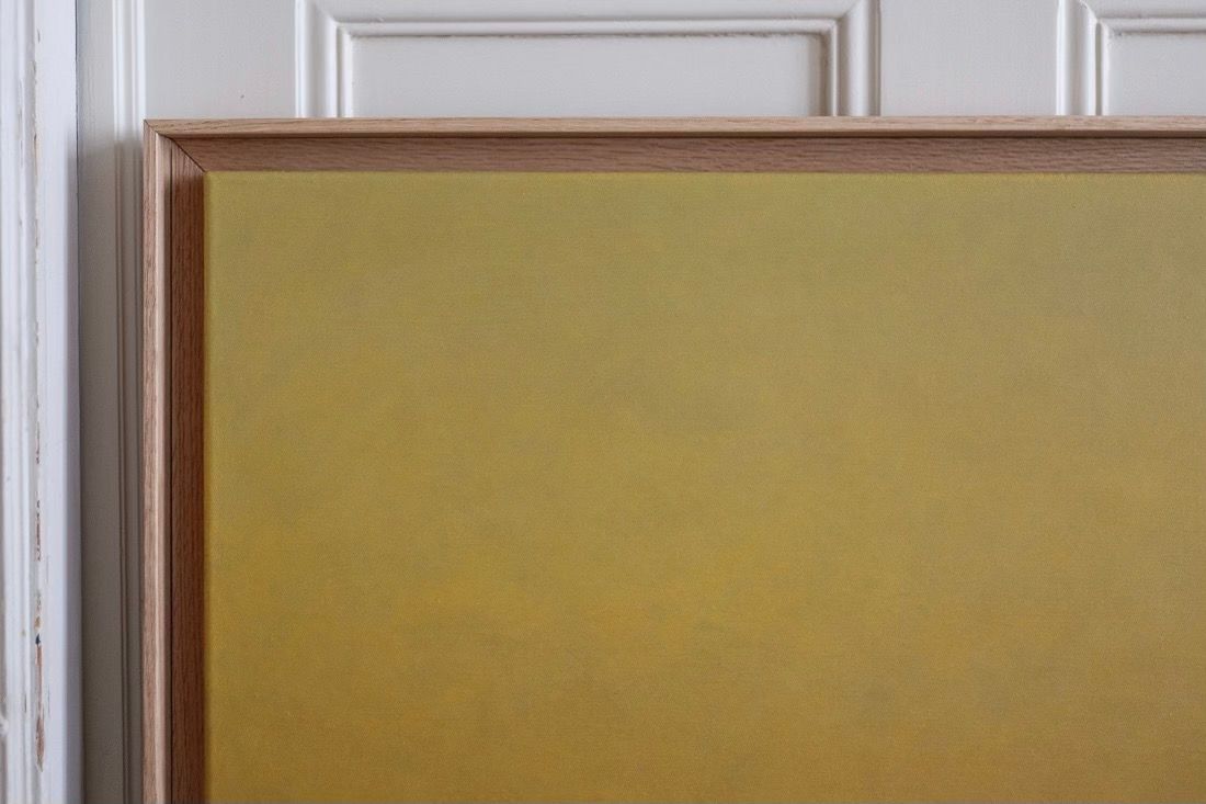 Rebecca von Matérn's 'Morning Hue' Painting, crafted in 2025 with a hard waxed oak frame, is an acrylic on canvas featuring a solid muted yellow. It elegantly adorns a white paneled wall, highlighting the junction of the framing and wall.