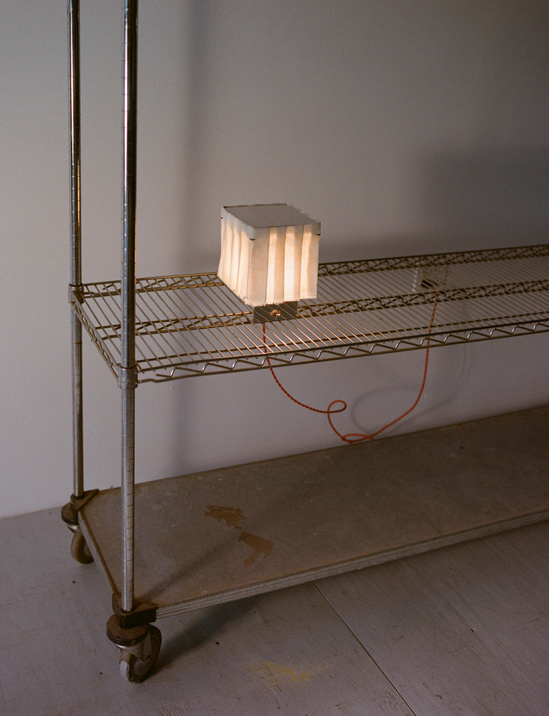White pleated cube table lamp on wire shelf styling detail