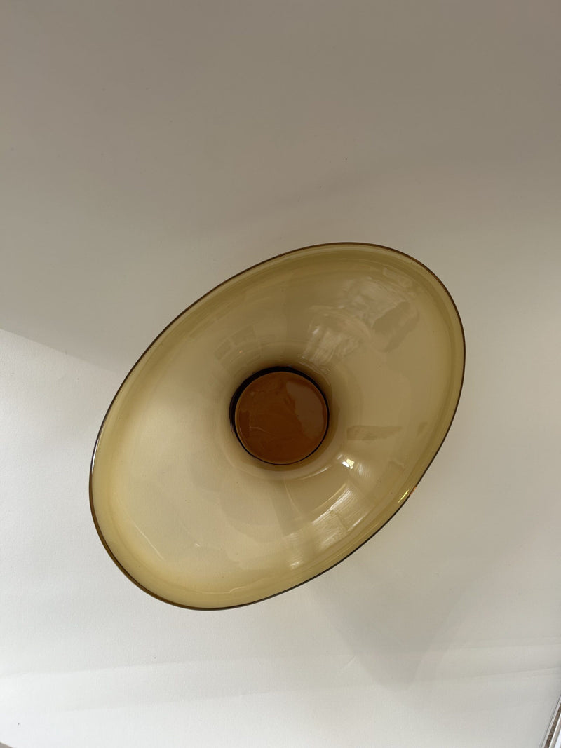 A circular fixture from Flock Studio, featuring a central brown accent against a white ceiling. The smooth, amber-hued surface of the Vintage Italian Murano Glass Dish emits a warm, soft glow reminiscent of classic glass artistry.