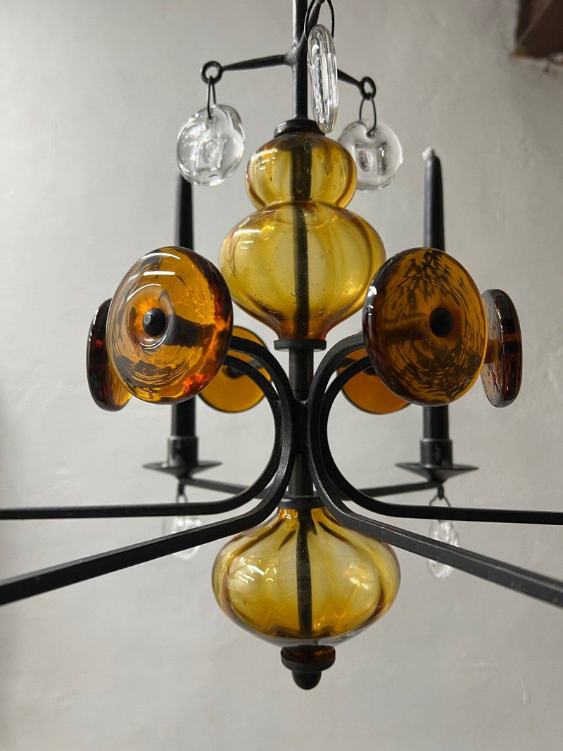 Amber glass chandelier detail with black iron frame and candle holders