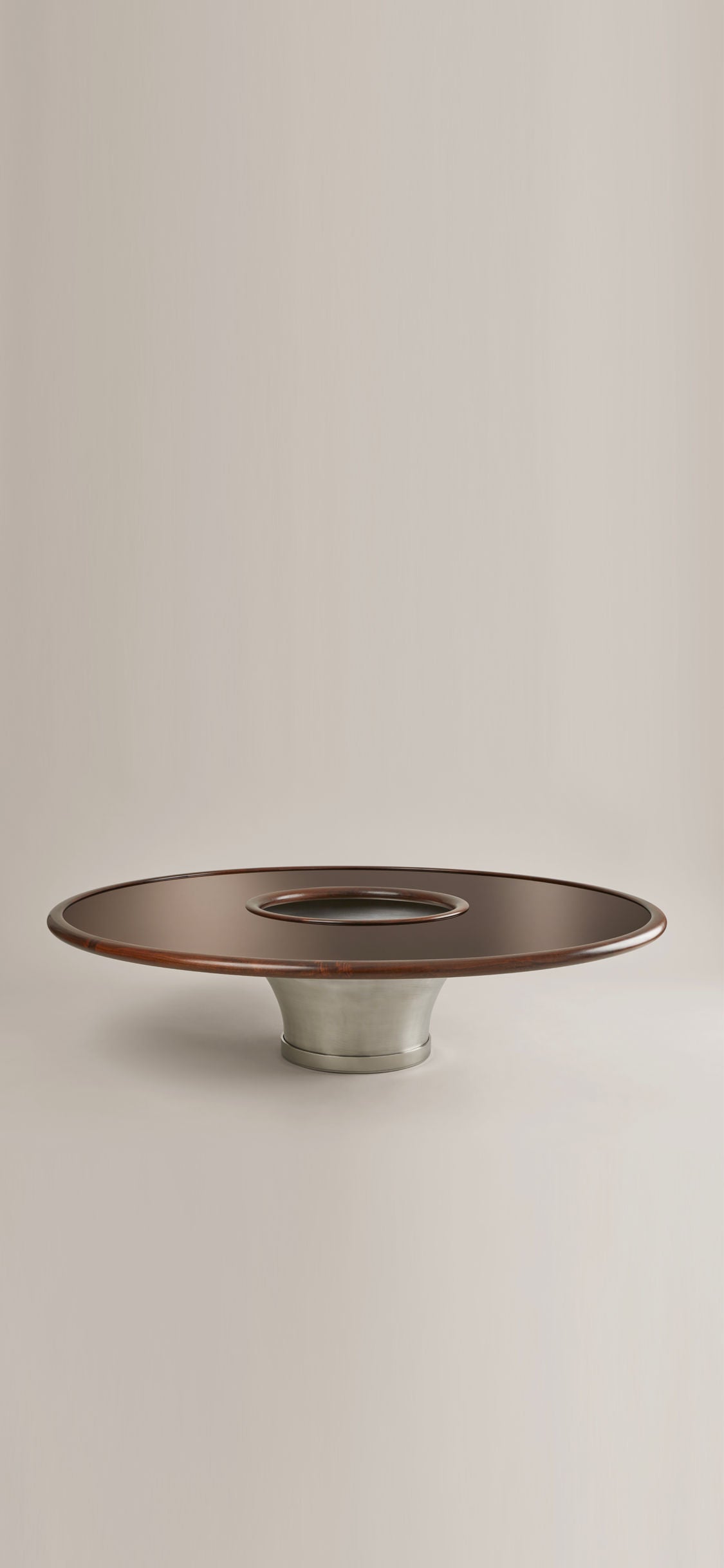 The "Loulou" Coffee Table by HAUVETTE & MADANI showcases a minimalist aesthetic with its sleek, modern design. It features a dark brown lacquered wood top paired with a silver metallic base, beautifully displayed against a plain light background.