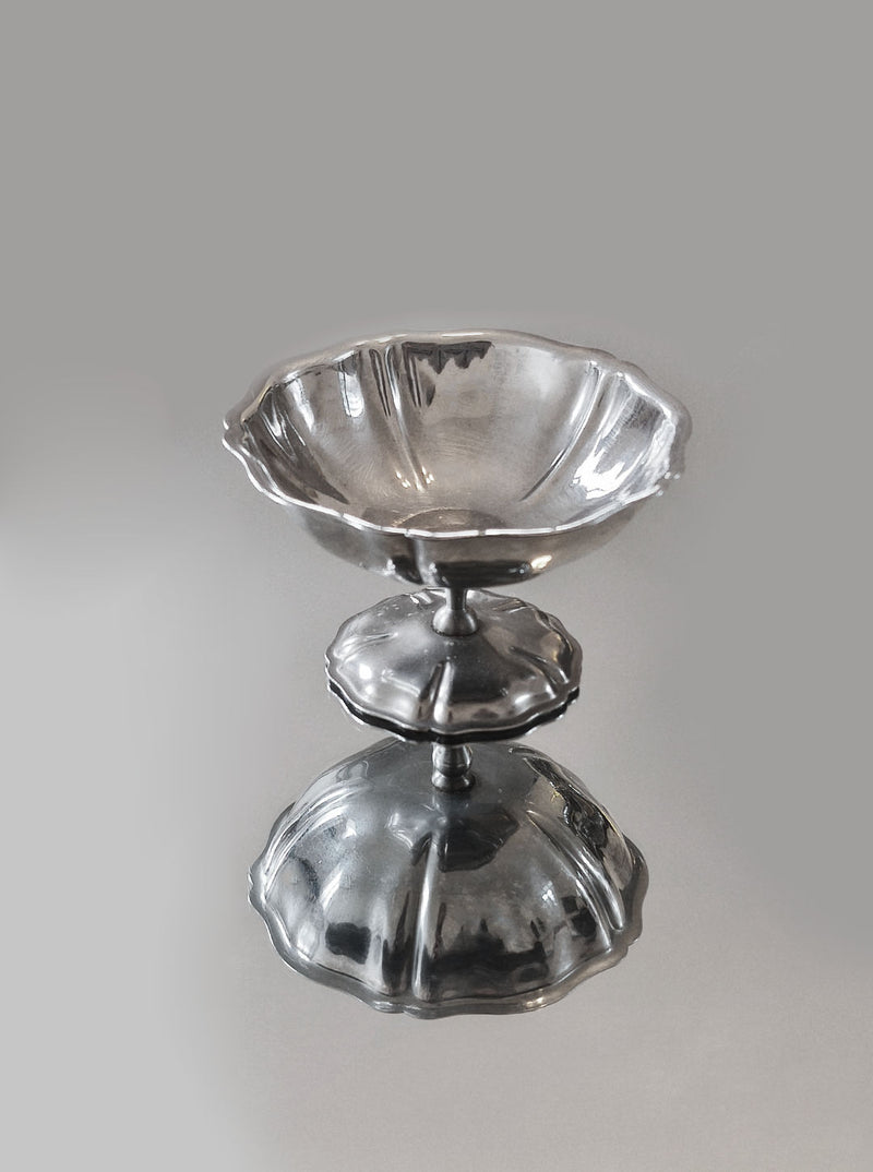 A flared, scalloped rim silver pedestal bowl with a reflective surface and matching base matches the aesthetic of the Les Objoies Set of 6 Dessert Cups, creating a mirror-like effect on its flat surface.