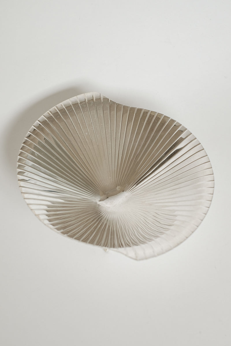 A close-up of the Silverplated Shell Dish by septembre studios reveals its large, intricate design on a light background, with fine radiating details and an irregular, wavy shape that exudes vintage appeal reminiscent of mid-century aesthetics.