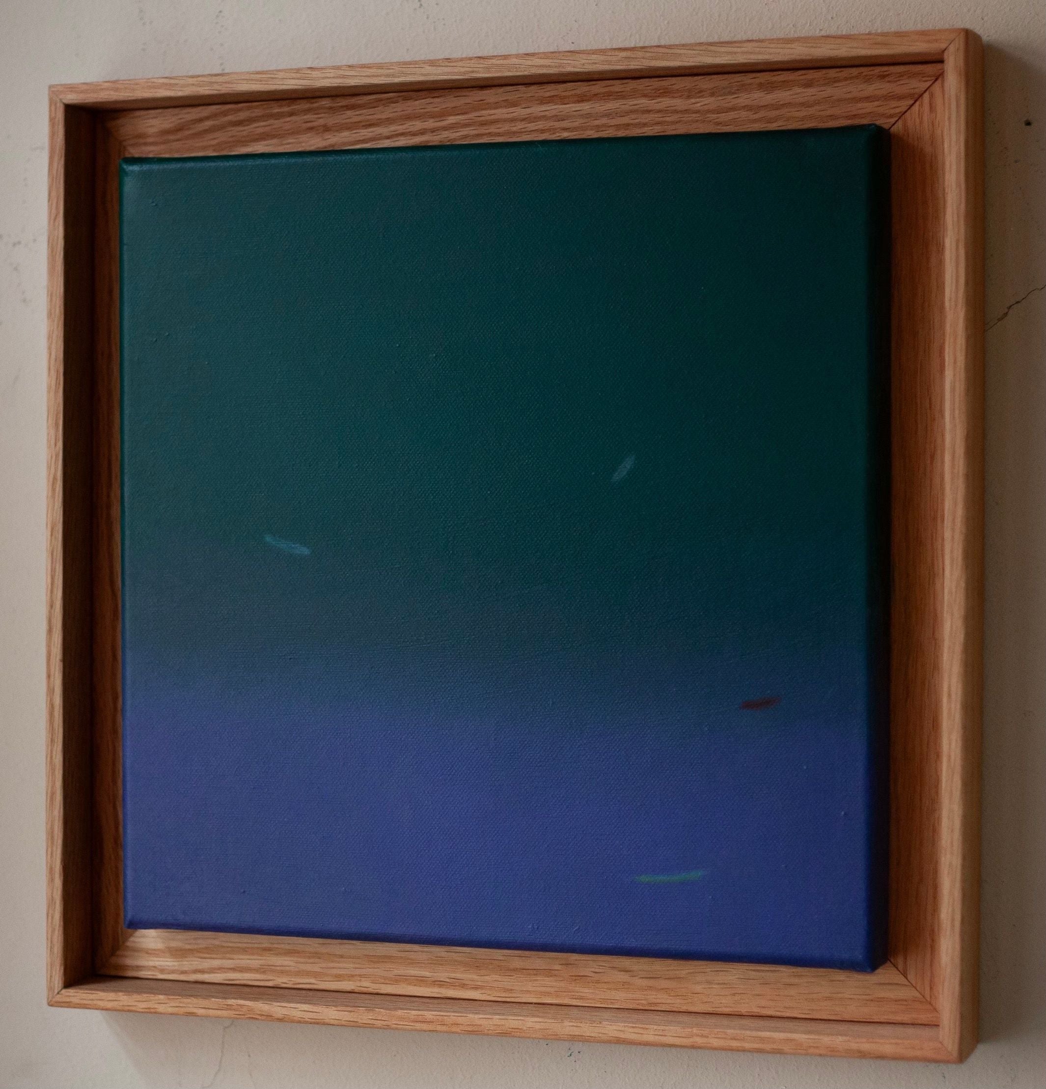 Fade into #2, 2024" by Rebecca von Matérn features a framed abstract painting that showcases shades of green merging into blue. This elegant piece is set in a hard wax oiled oak shadow frame and measures 36x36 cm. The canvas displays subtle light streaks or brushstrokes for enhanced texture.