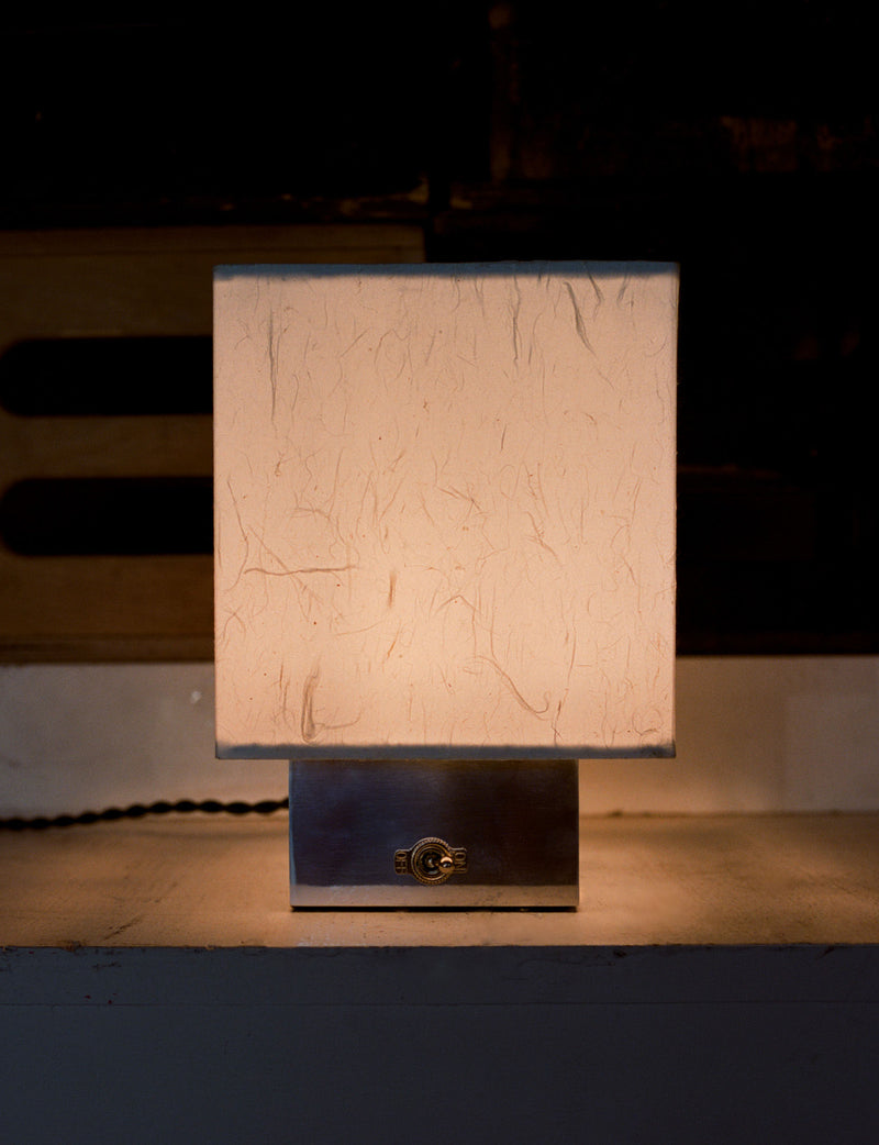 Modern cubic table lamp with textured beige shade on dark base