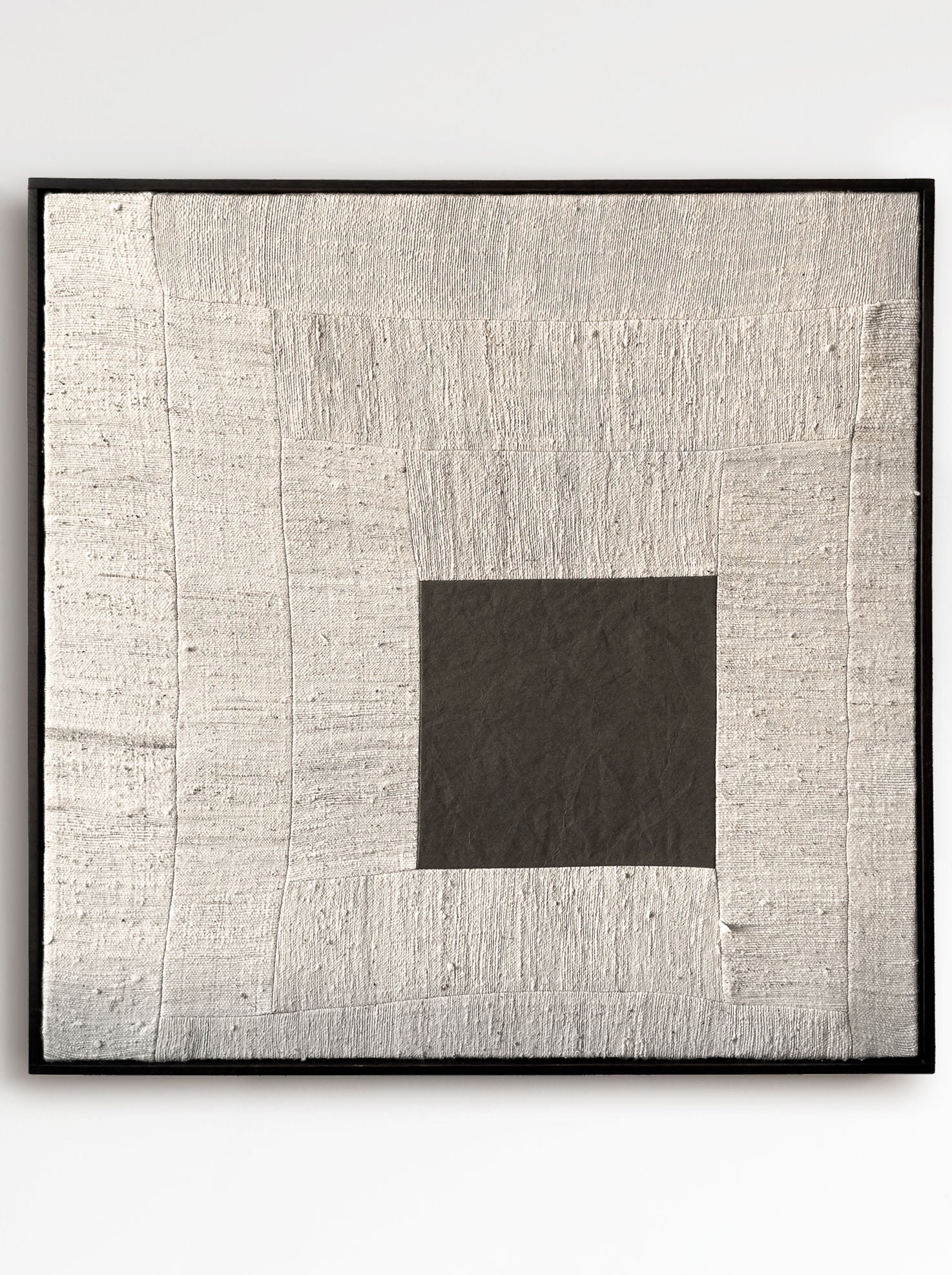 The framed artwork "Are You Open?", 2025, by Bec Kirby, features a minimalist geometric design with a textured silver and gray surface. A dark gray square centers woven metallic-like fabric panels surrounded by a solid oak frame with handwoven kapok fiber cloth accents.