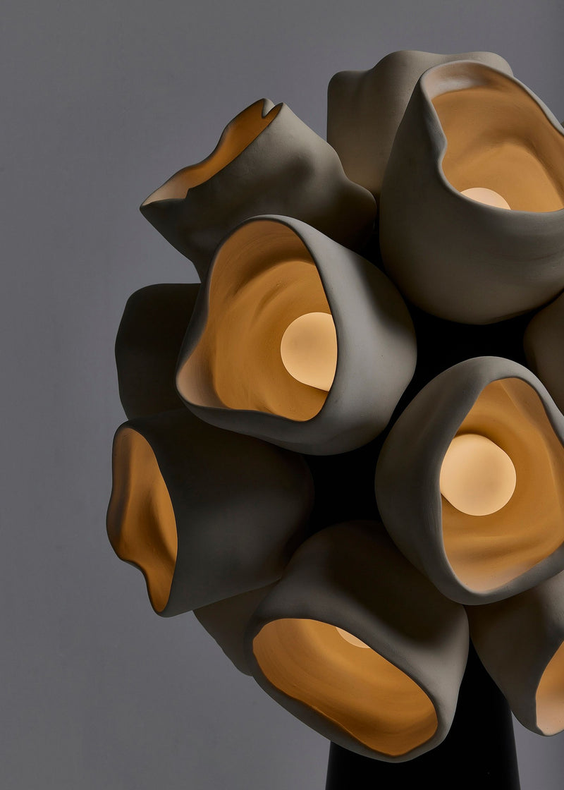 Contemporary sculptural floor lamp with organic curved forms in matte gray and warm amber tones