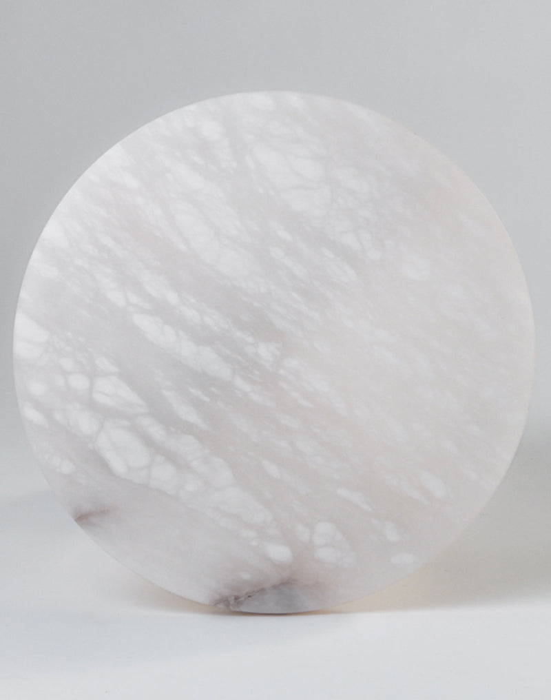 Round alabaster side table showing natural stone veining and translucent surface
