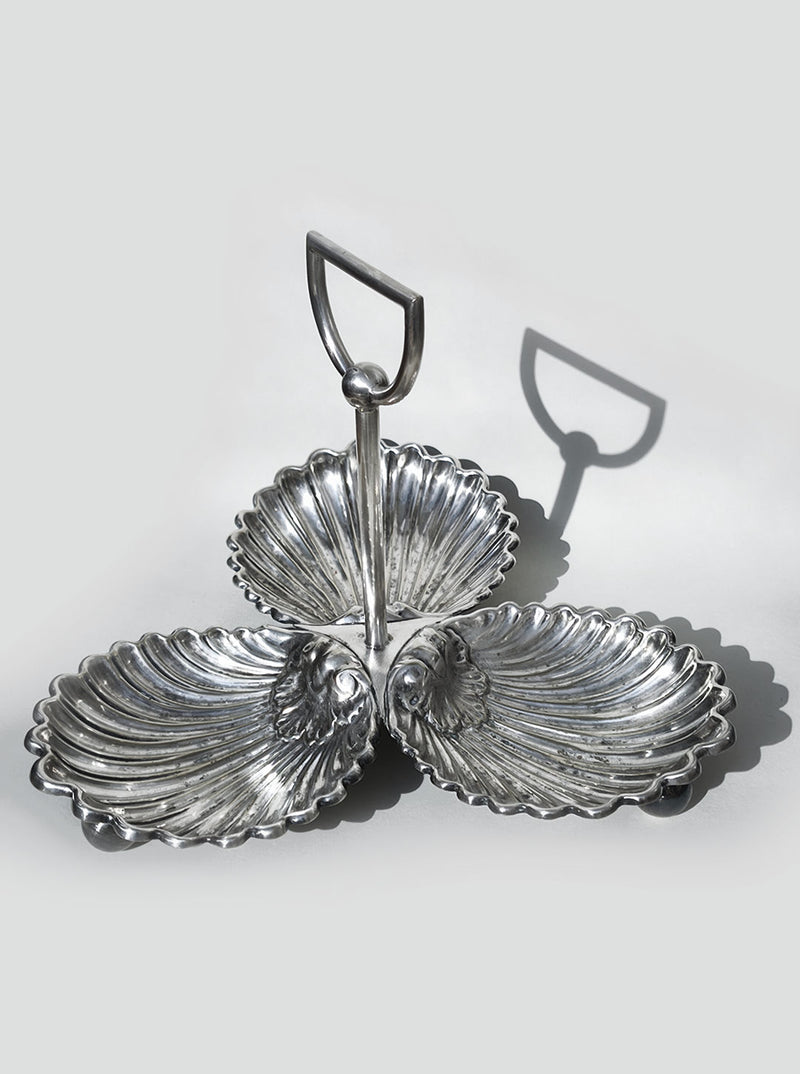 The Les Objoies Large Silver-plated Triple Tray features shell-shaped compartments and a central handle, casting a distinct shadow on a light gray background.