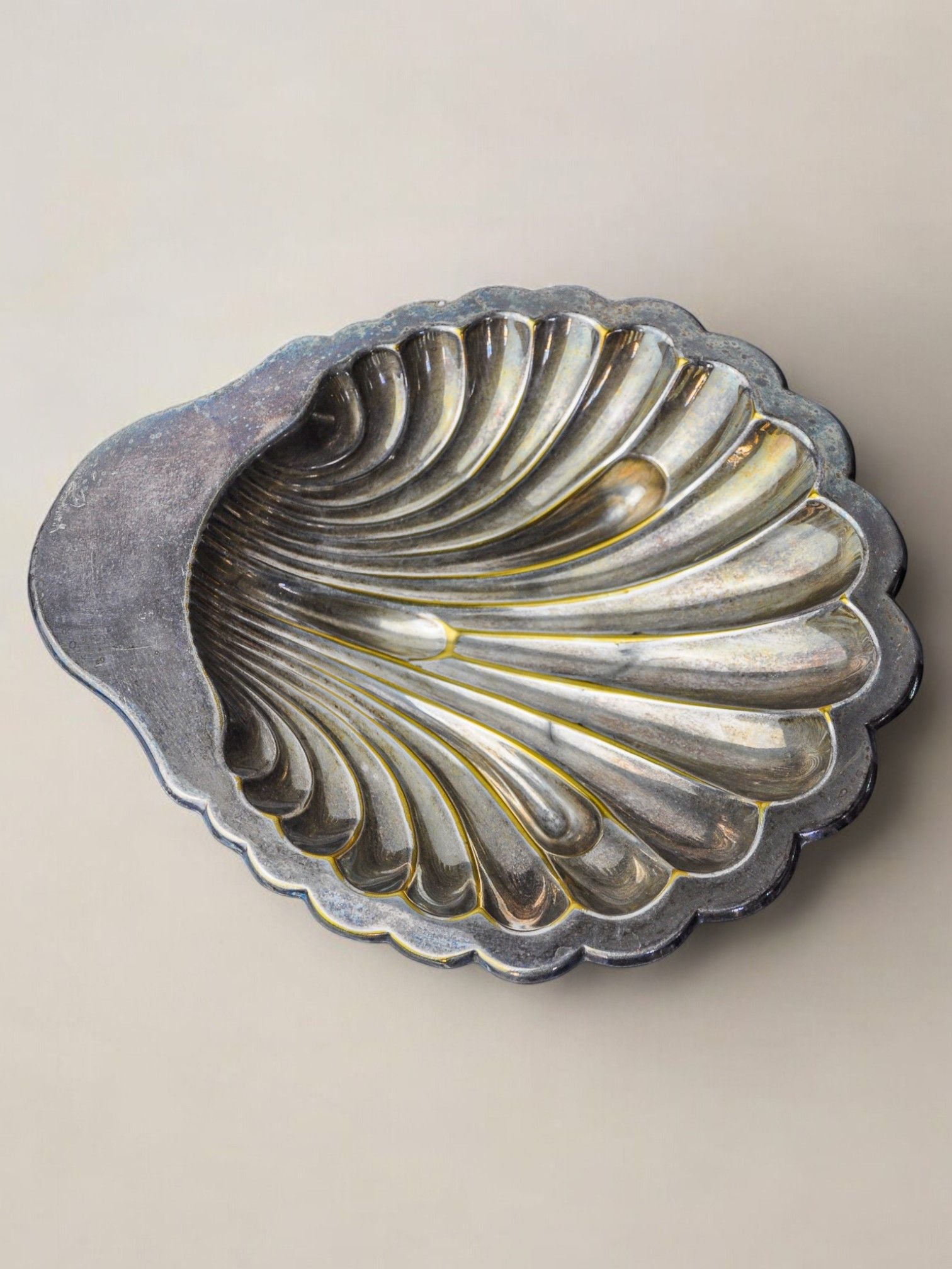 A vintage Italian design silver-plated shell-shaped vide-poche by Malamar Studio from 1970 features a detailed ridged interior and tarnished finish, elegantly displayed on a neutral background.