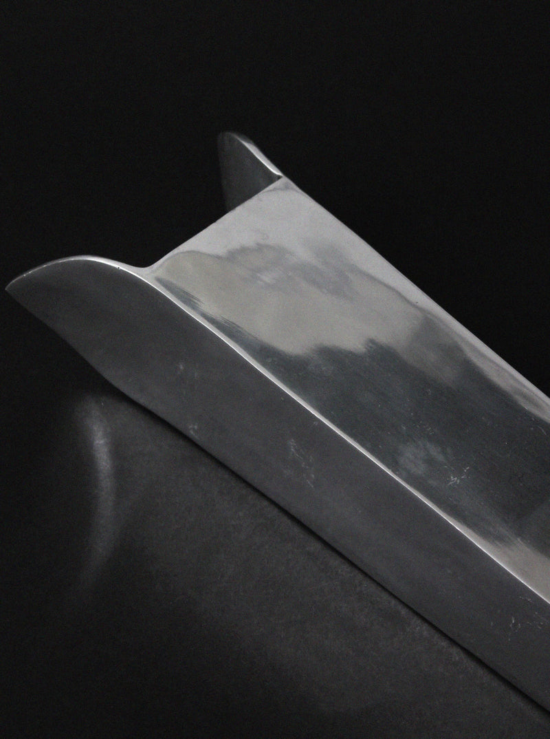 Contemporary aluminum vase curved silhouette against dark background
