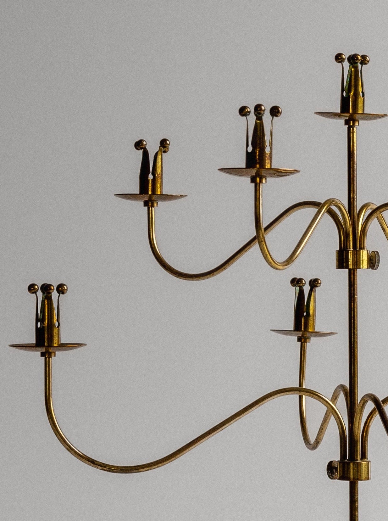 The Brass Candelabra by Spigel, Sweden, 1950s, features five gracefully arched arms ending in candle holders. Reminiscent of Ystad Metall and Scandinavian design from the era, this brass candelabra showcases a smooth, shining surface and is set against a neutral grey background.