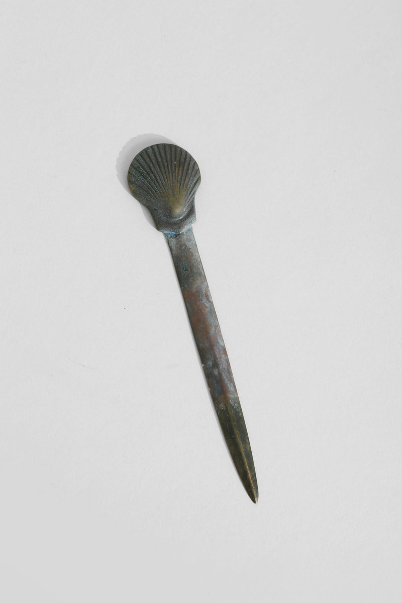 Brass shell letter opener with patina finish showing side profile