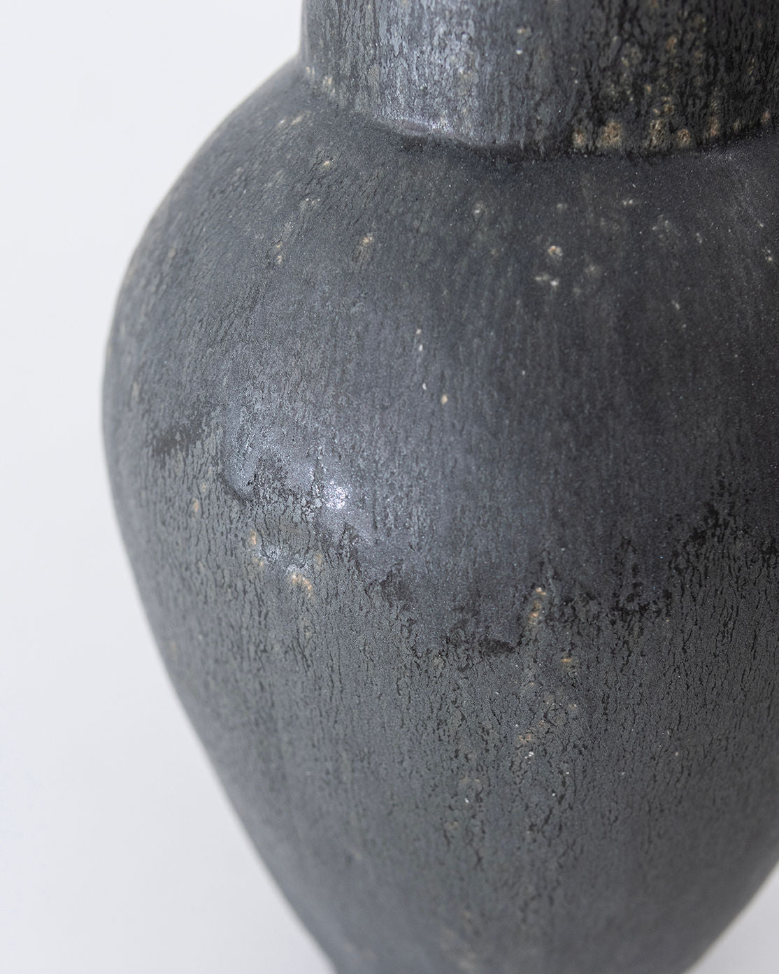 Close-up of the 'Isolated n.36' Vase by Canoa Lab—a textured, dark gray ceramic piece with a matte finish and subtle streaks, highlighting its handmade elegance against a plain light background.