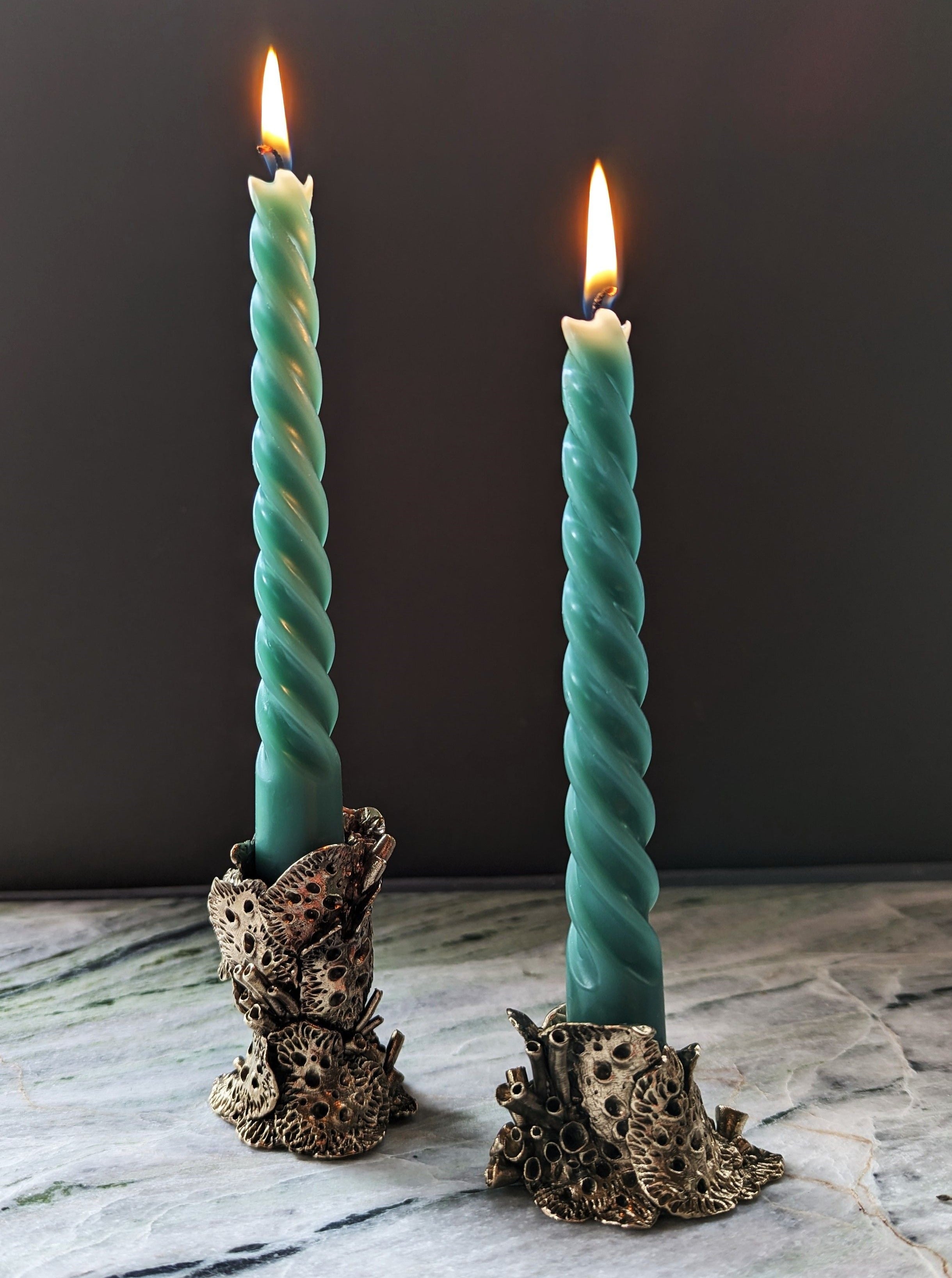 Bronze lichen candle holders on wooden table with lit candles