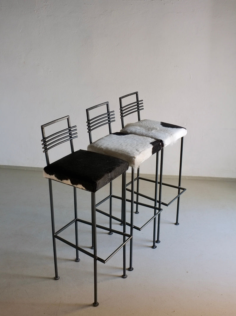 Three vintage wrought iron bar stools with cowhide seats 1990s
