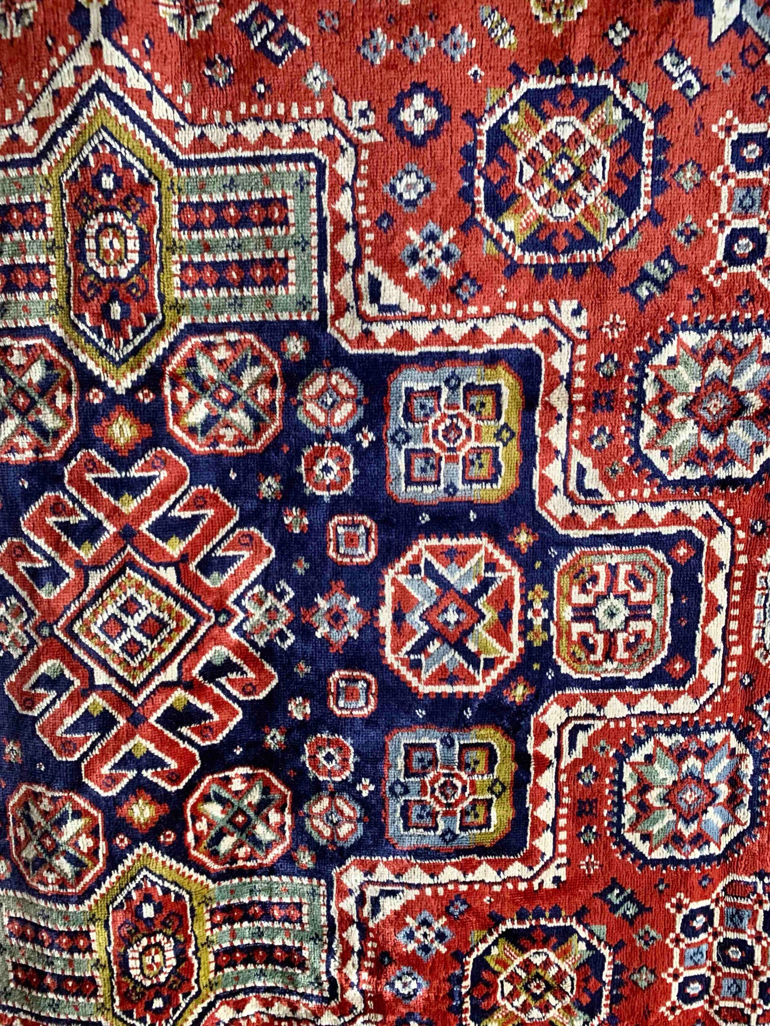 A close-up of the Veter Vintage Silk Oriental Duvet Cover - Rug, showcasing vintage geometric motifs in red, blue, cream, and gold, with symmetrical designs woven from a luxurious silk-wool blend.