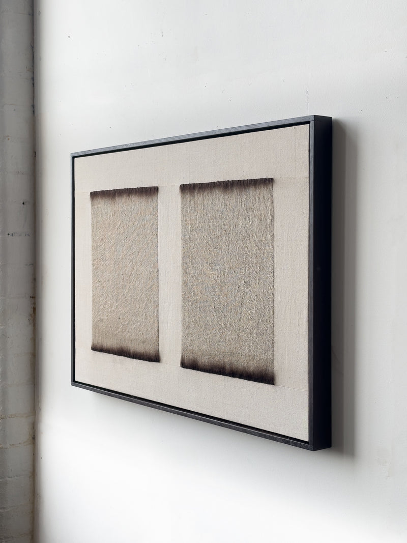 The framed artwork "Twin," 2025 by Bec Kirby, features two textured rectangular sections on a white wall. Made from antique hemp material, it lends a minimalist and tactile appearance, with shadows enhancing its depth.