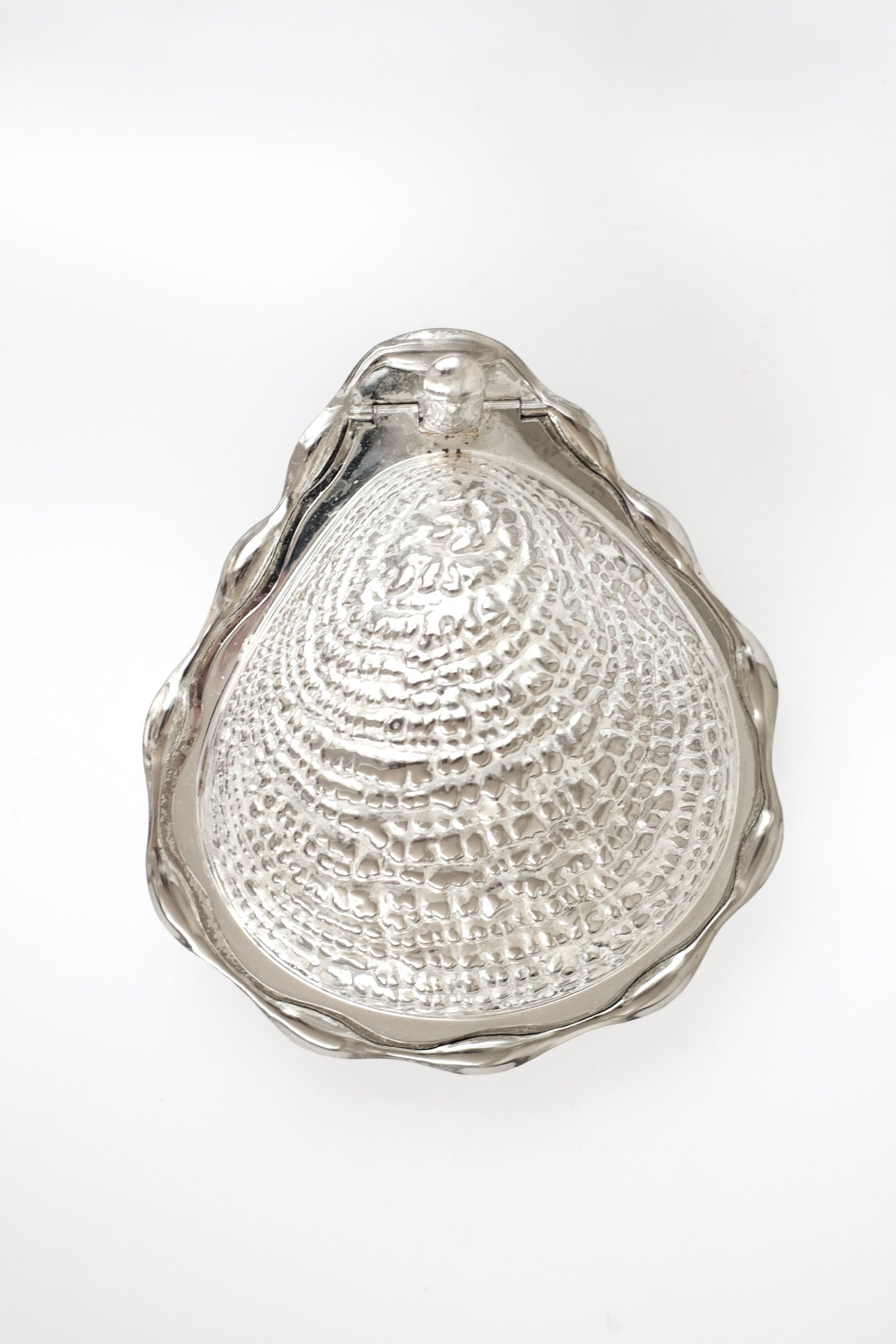 The Shell Butter Dish by septembre studios features a shiny, metallic vintage scallop shell design with a textured surface and wavy edges, shown against a plain white background.