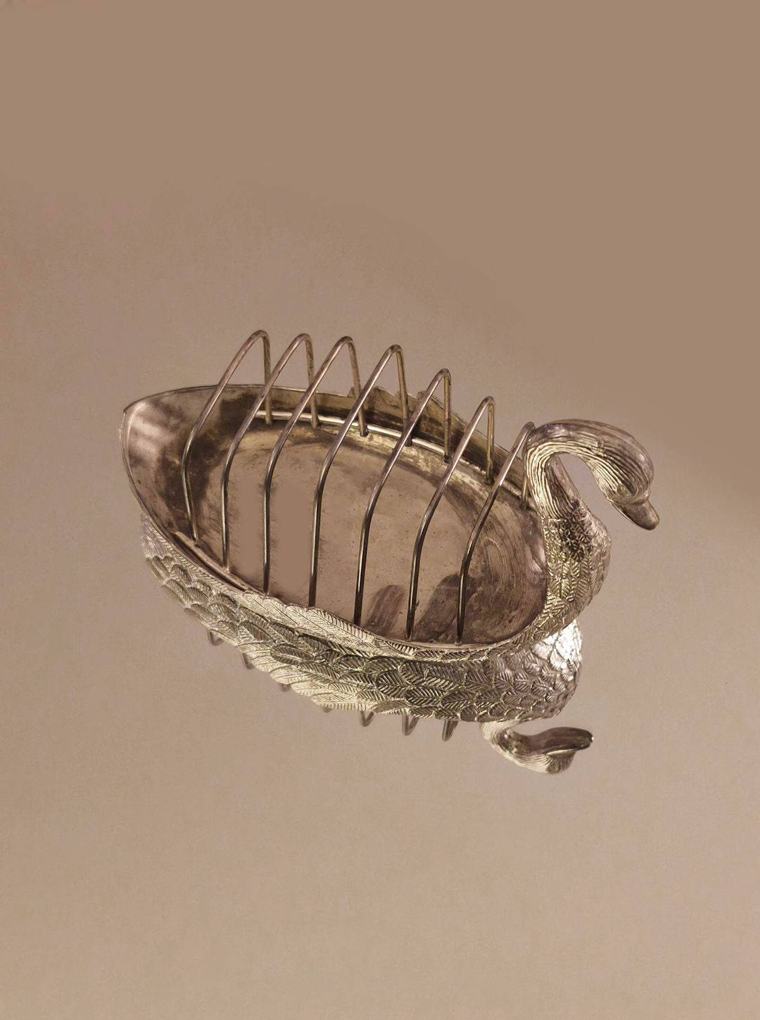 Introducing the Swan Toast Rack by Les Objoies: a stunning silver-plated toast holder crafted in the graceful shape of a swan. Its body forms the base, with an elegantly curving neck, and it features multiple vertical slits to hold slices of toast. The image showcases this breakfast table accessory against a soft, neutral background.