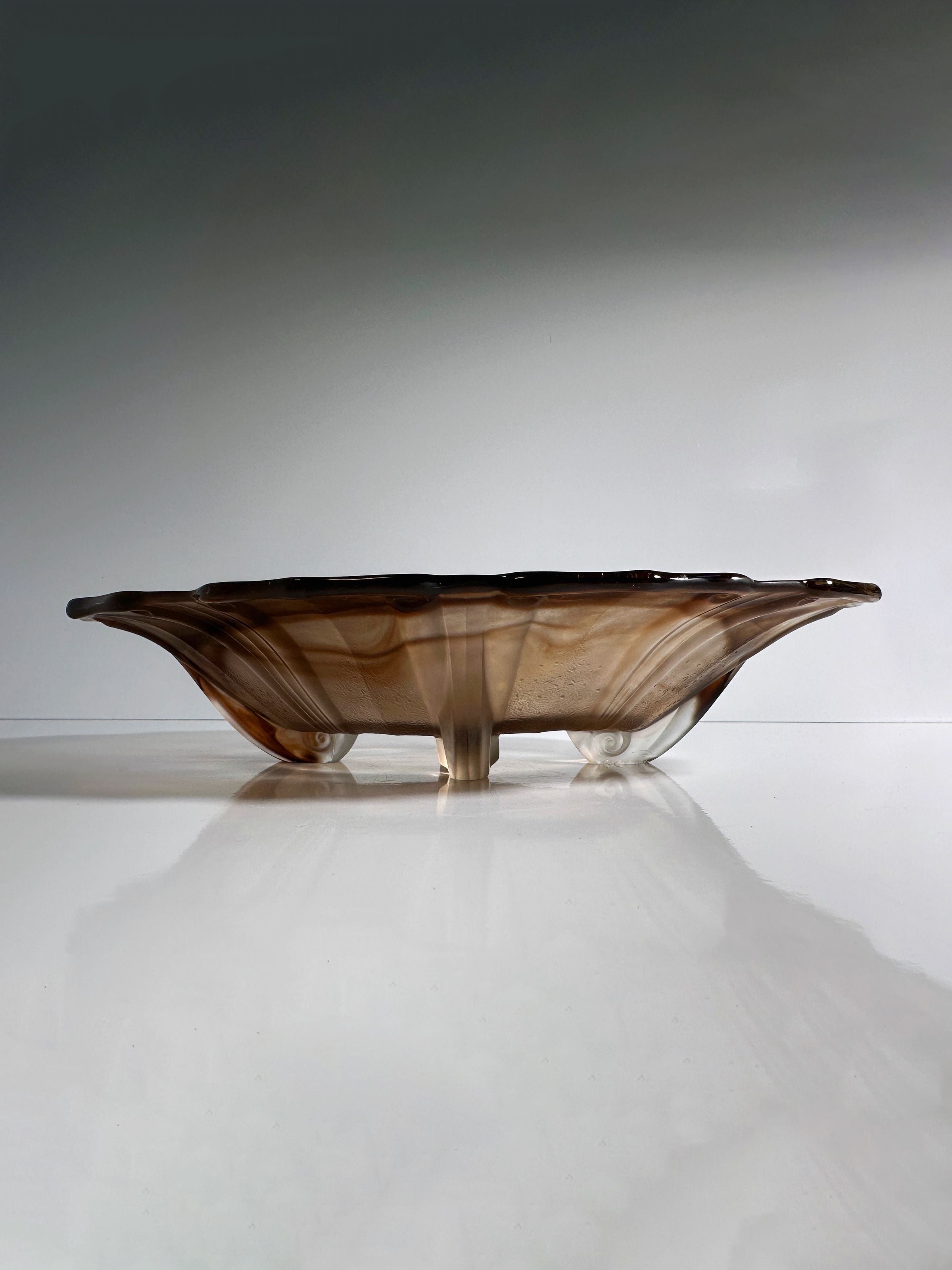 The German Art Deco Cloud Glass Bowl, circa 1930 by Dodo Vintage, is a low, brown glass piece with a wavy edge and subtle marbled pattern. Supported by small transparent legs against a plain background, it evokes Walther Glas's elegance and sophisticated simplicity.