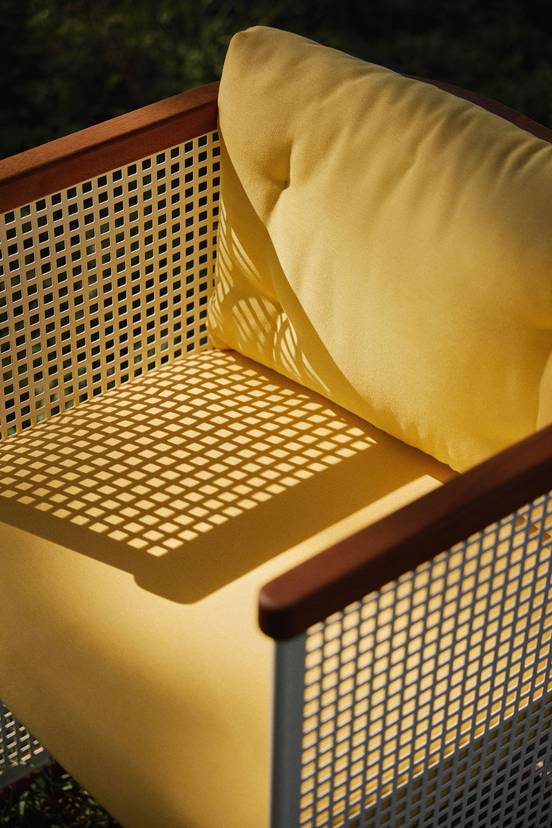 Yellow cushioned outdoor chair with cane webbing and wood frame