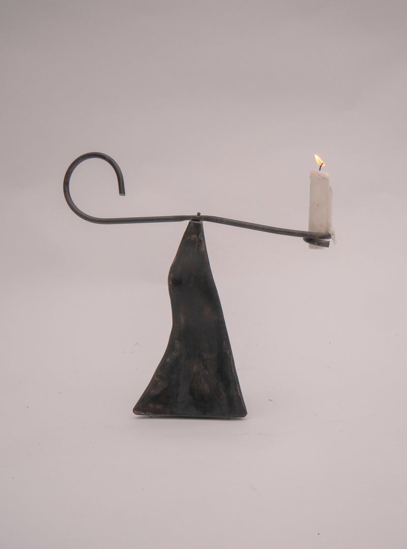 Modern balance candle holder with lit candle on triangular base