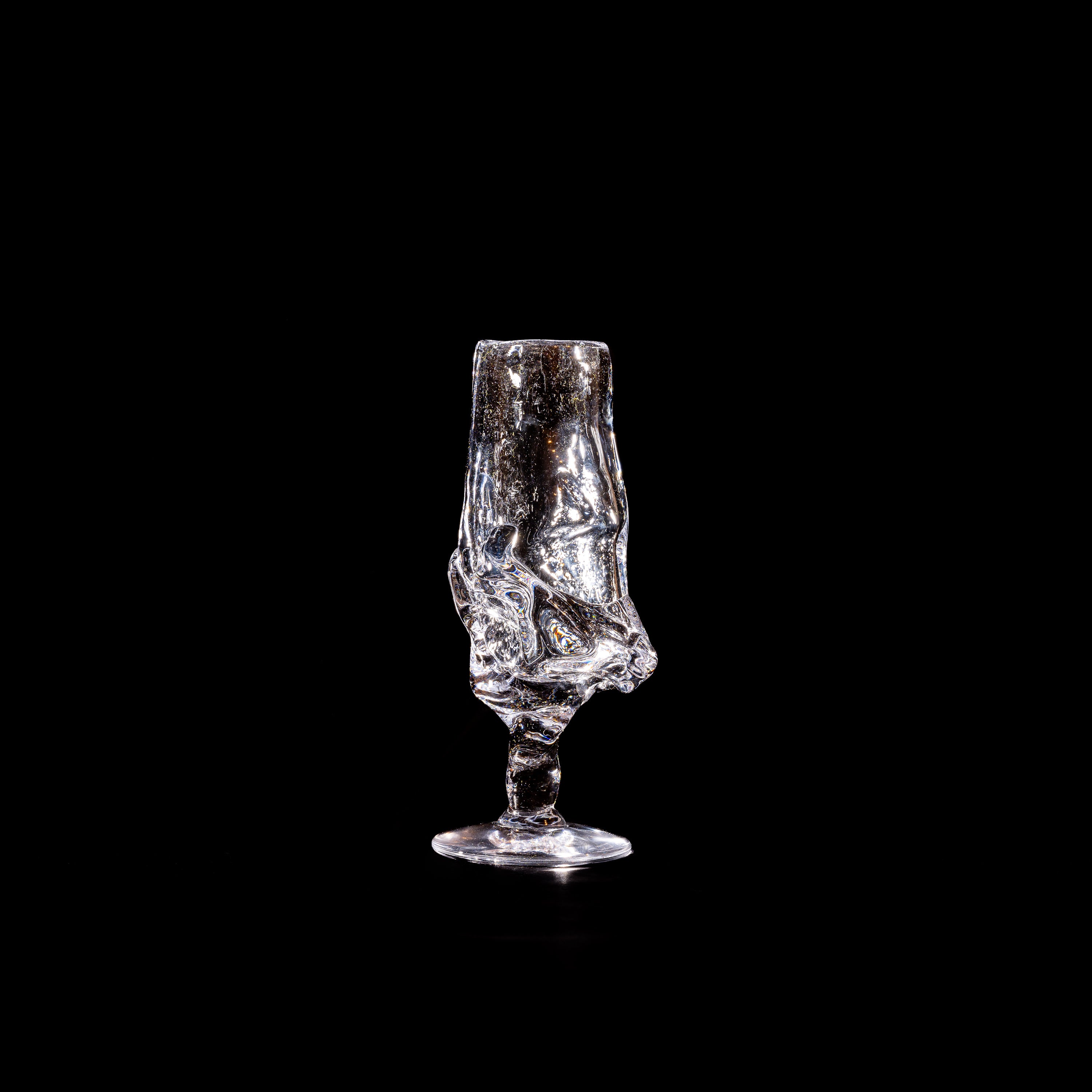 The Table Goblet by Szkło Studio features a unique, twisted glass-blown design, crafted by Aleksandra Zawistowska and displayed against a solid black background.