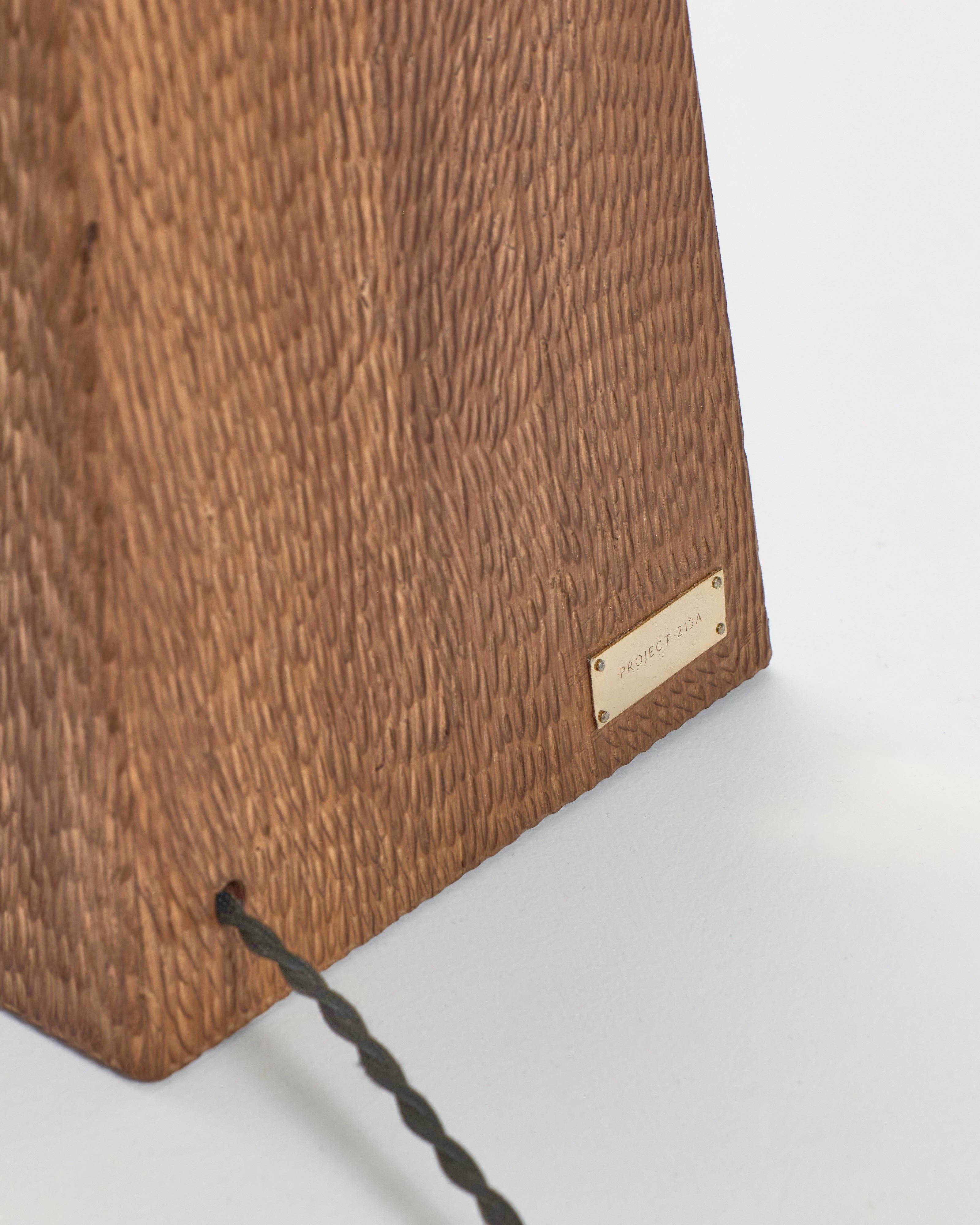 Coquette Floor Light — close-up of textured wooden base with brass label