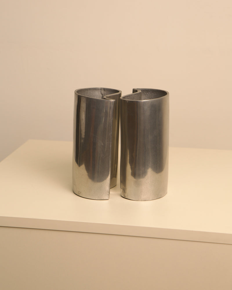 Two polished aluminum cylindrical vases interlocking in yin yang formation