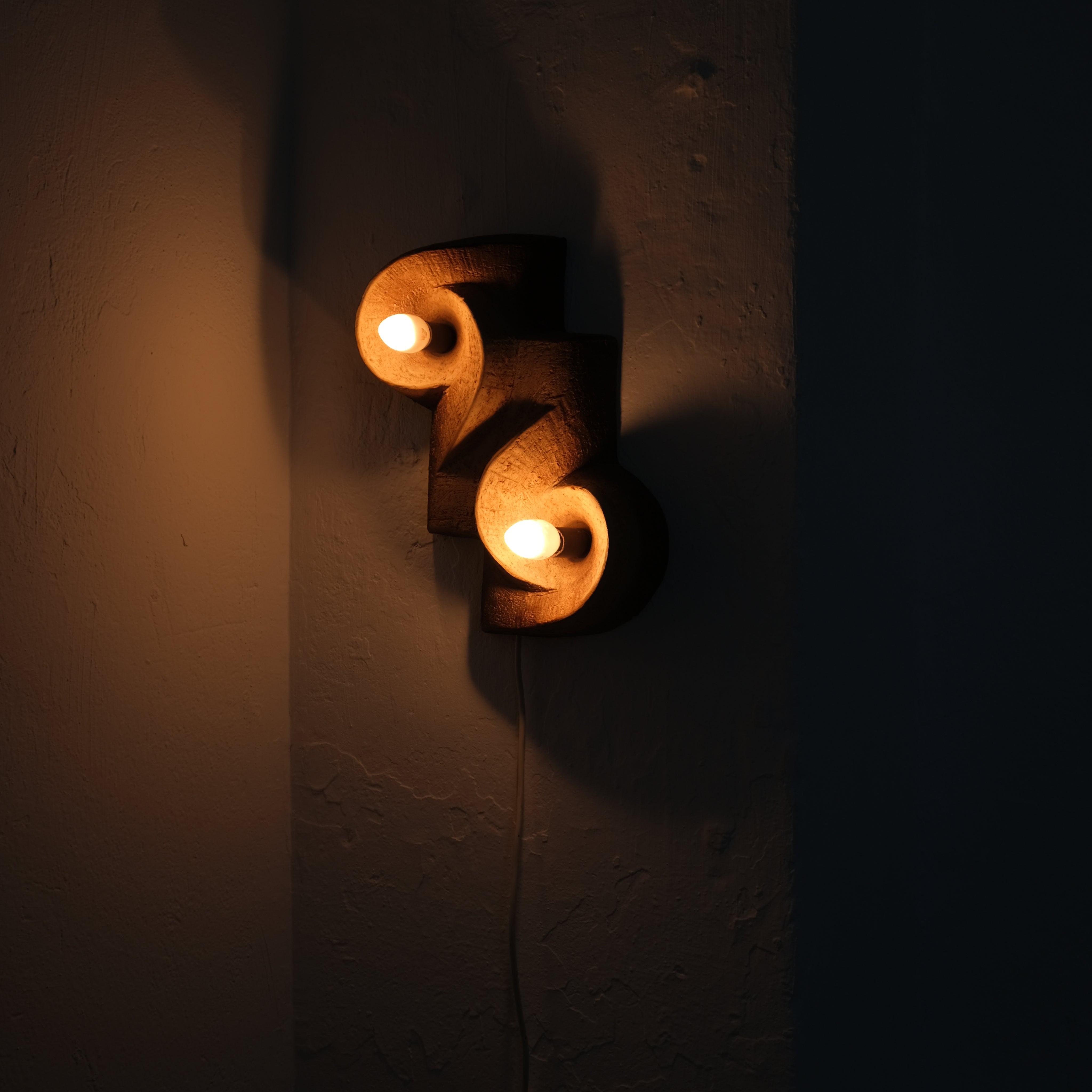 Brutalist Ceramic Wall Sconce, Netherlands, 1960s — illuminated on textured wall in dark setting