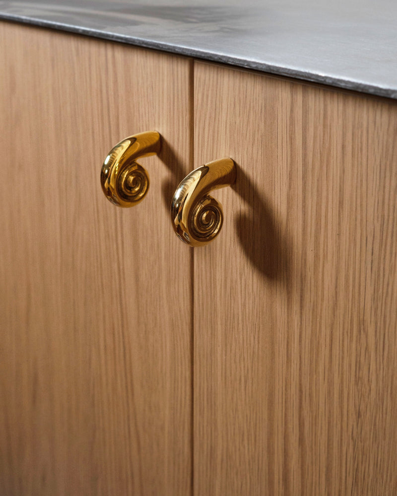 Noelle Knob - Brass — close-up of brass knob on wooden cabinet