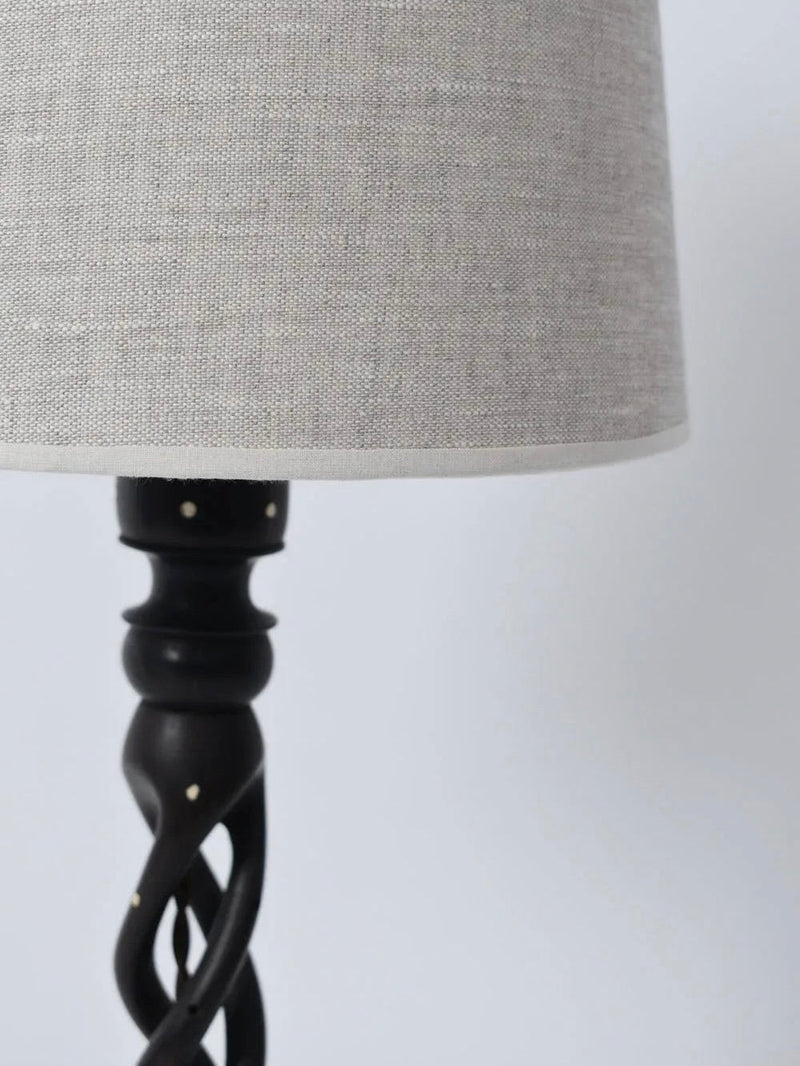 A close-up of the Turned Wood Twist Lamp from Barracuda Interiors (1960s) shows its light gray fabric shade and dark, twisted carved base set against a plain, light background.