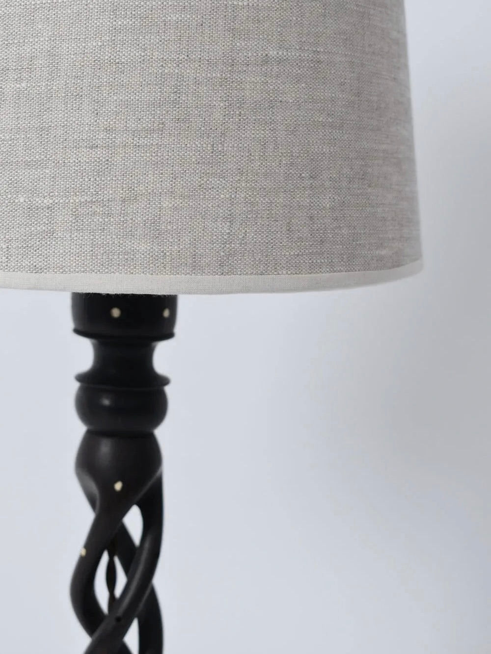 A close-up of the Turned Wood Twist Lamp from Barracuda Interiors (1960s) shows its light gray fabric shade and dark, twisted carved base set against a plain, light background.