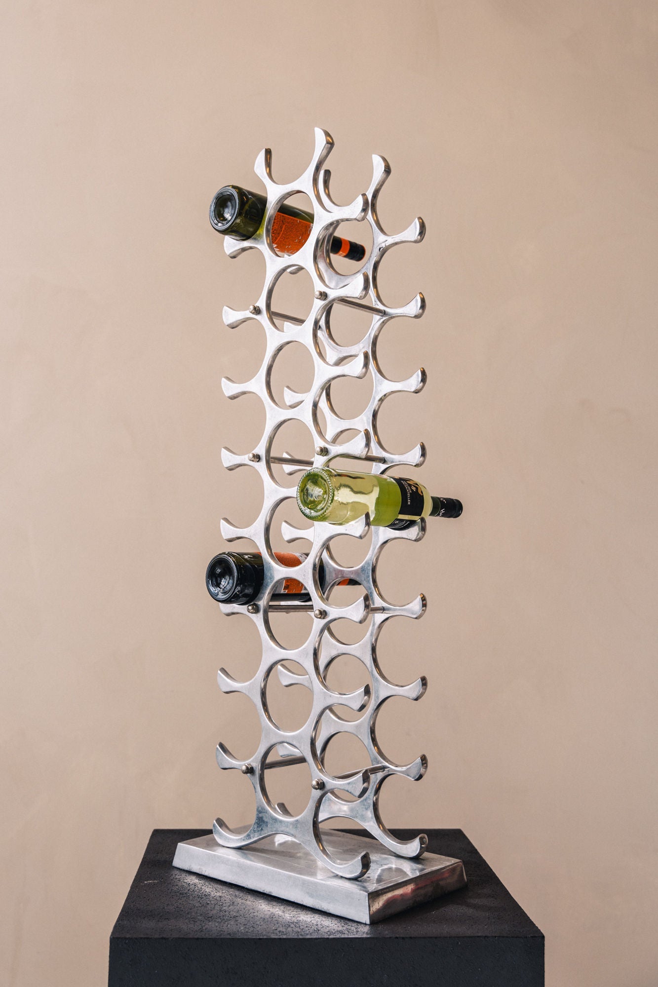 Modern chrome wine rack with sculptural design holding bottles vertically