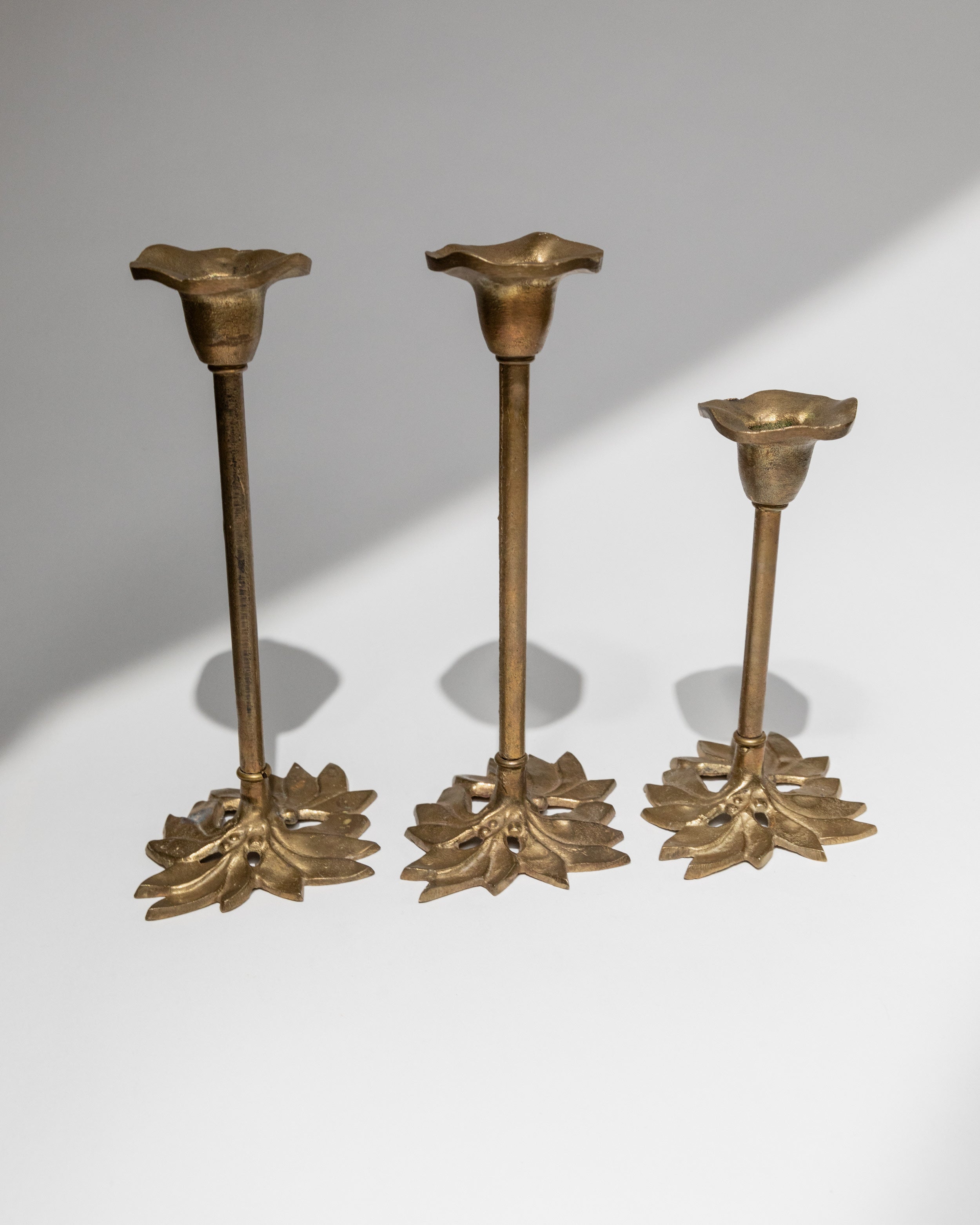 Set of three vintage brass candle holders with floral bases Italy