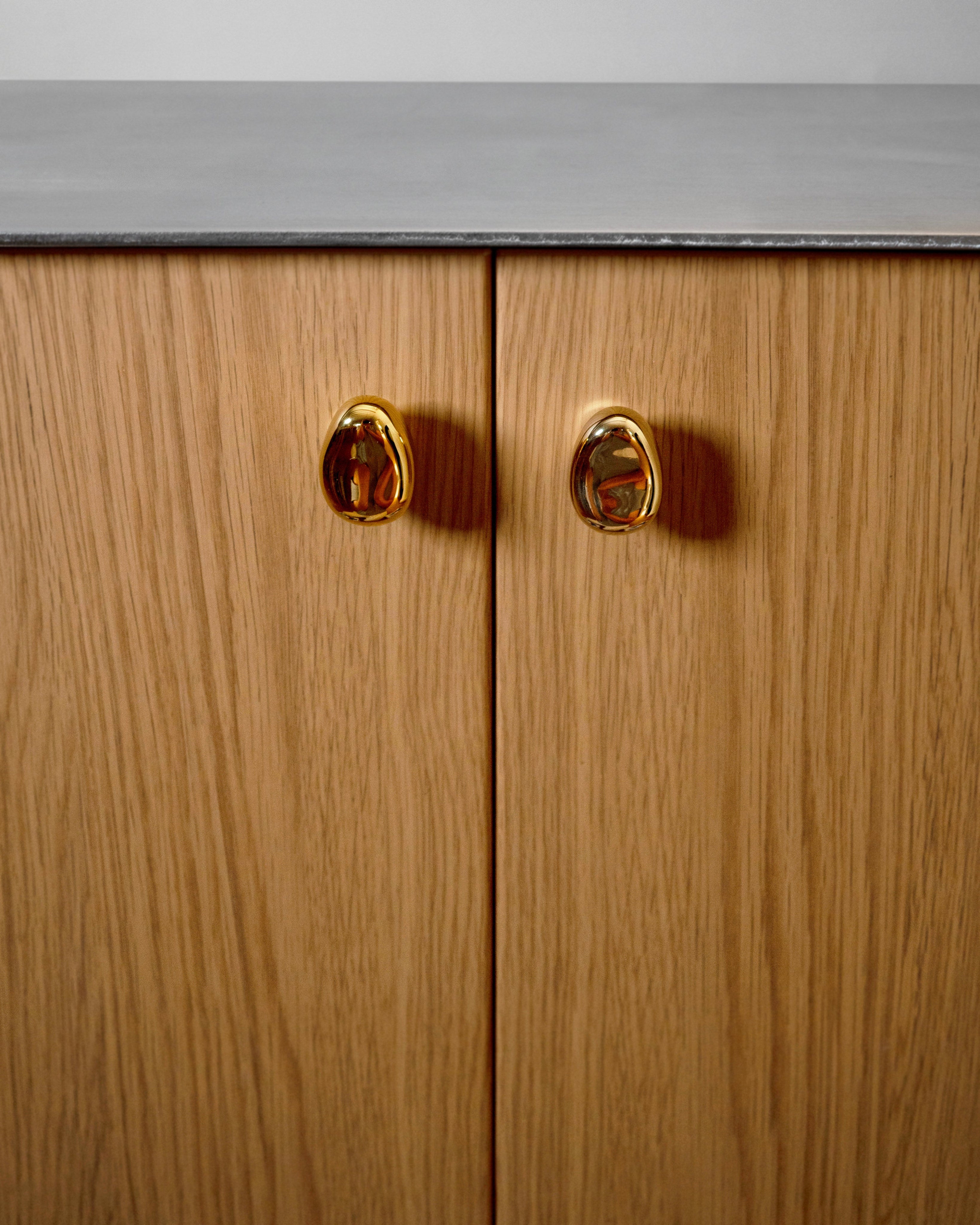 Rud Knob - Brass — side view on wooden cabinet doors