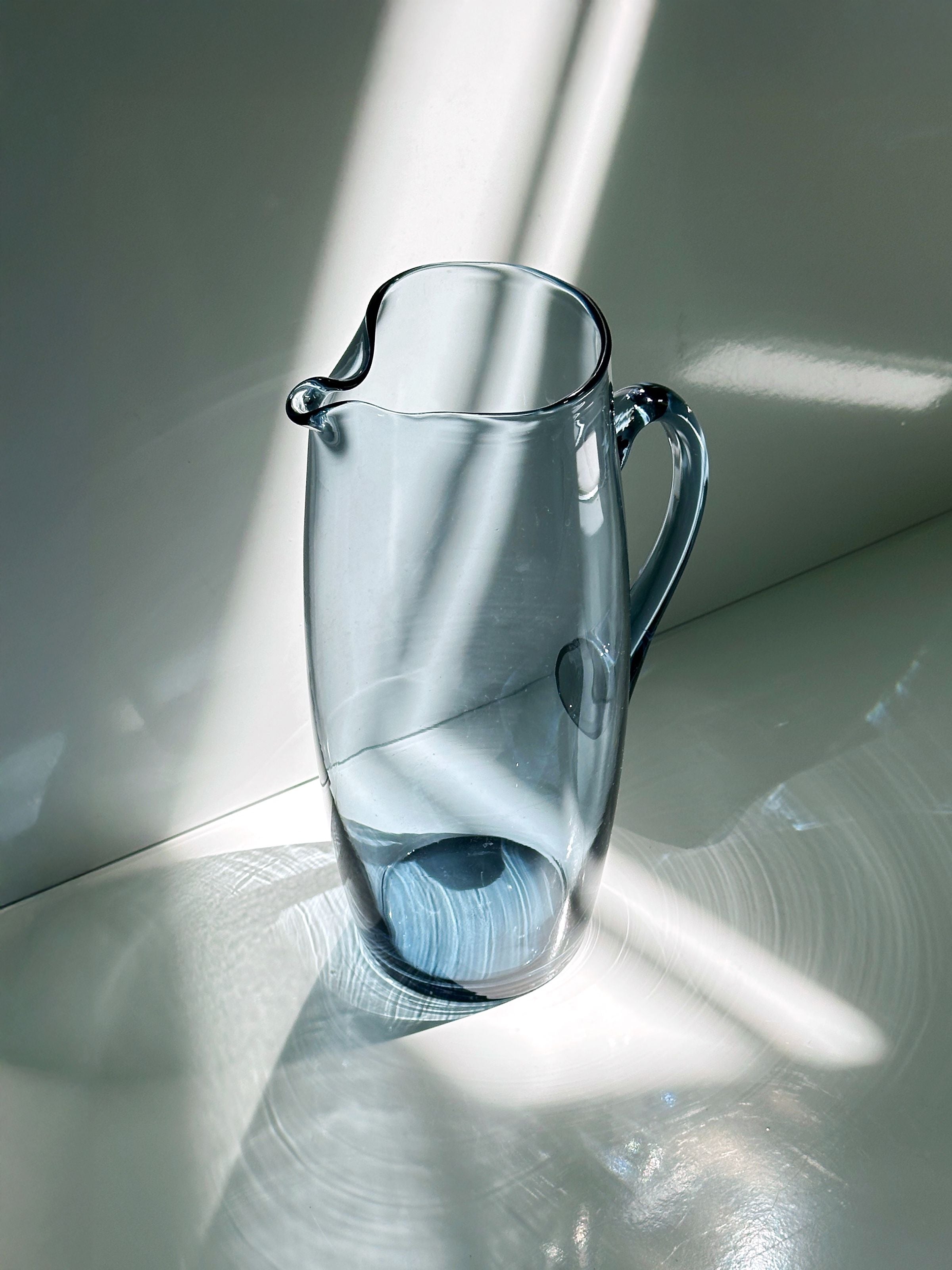 Clear glass carafe with elegant handle in natural sunlight