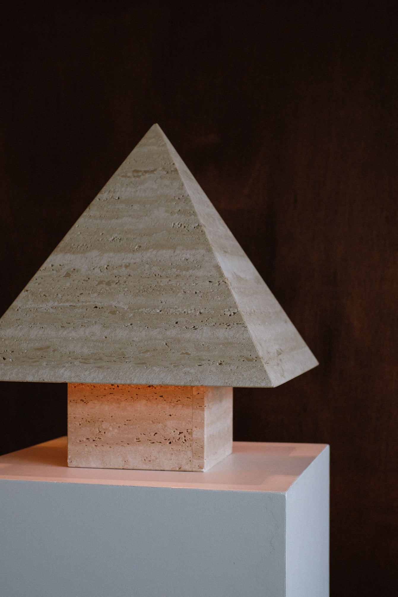 Travertine Pyramid Table Lamp — side angle on white pedestal