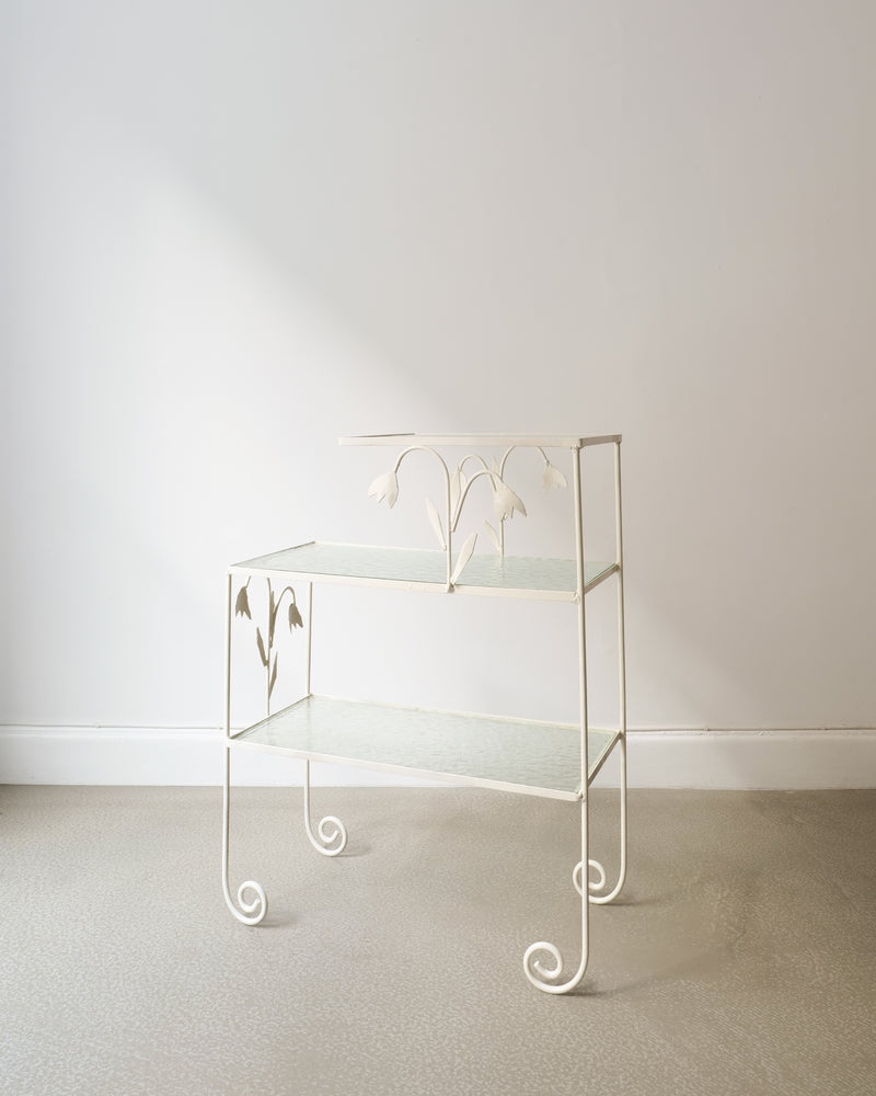 White metal tiered side table with glass shelves and scrolled legs
