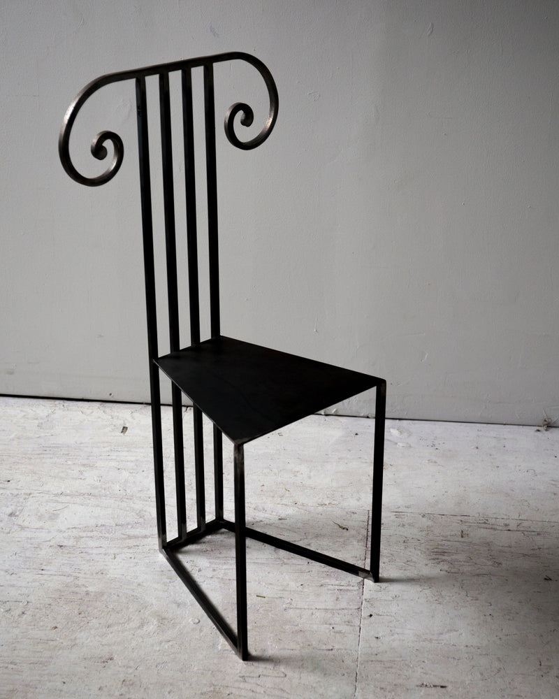 Black metal Column Chair with vertical slat back and curved scrolls
