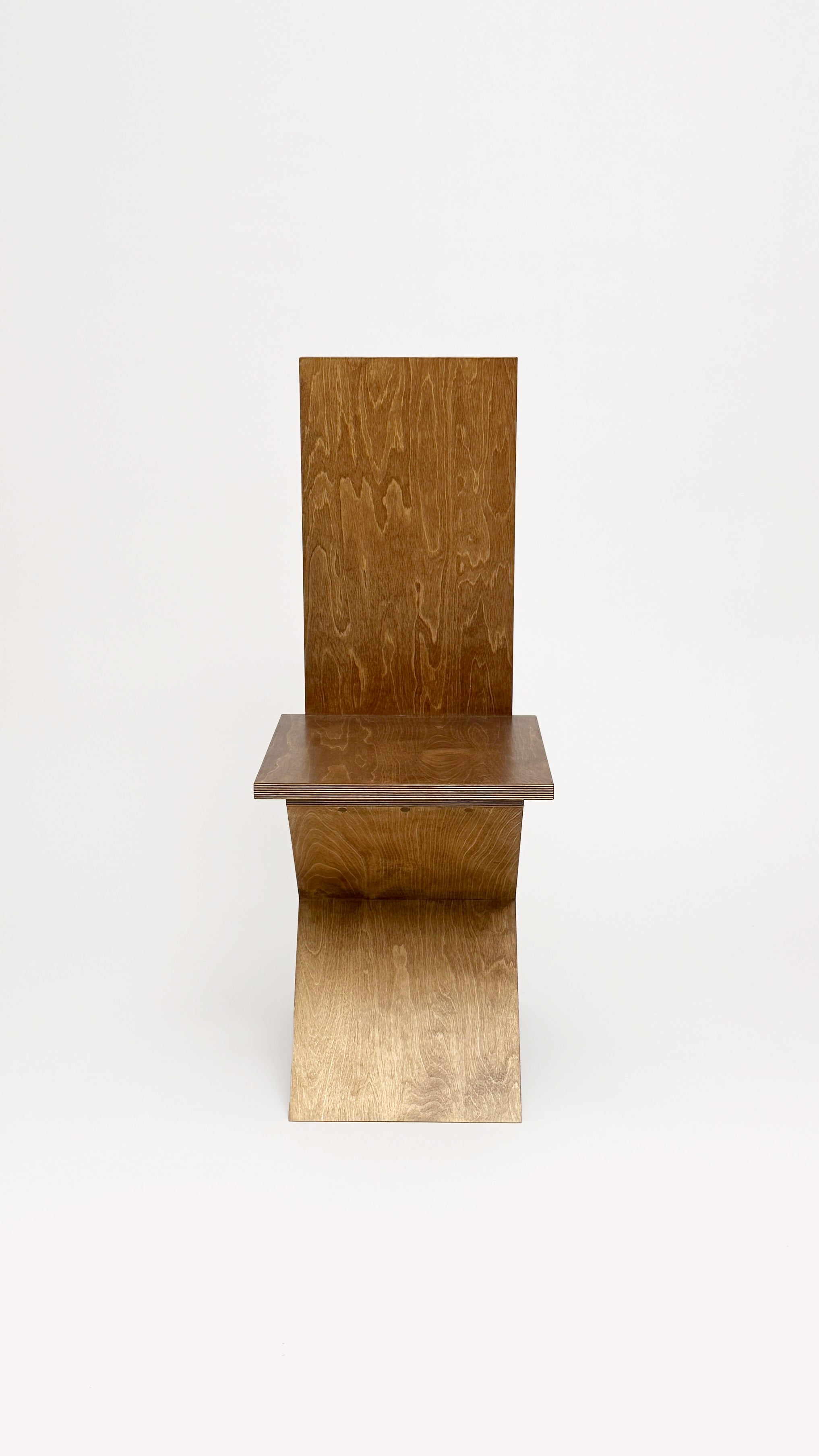 The Flat Pack Chair by Goons features a minimalist wooden design with a flat, rectangular seat and backrest plus a curved base, shown against a plain white background—crafted by GOONS.