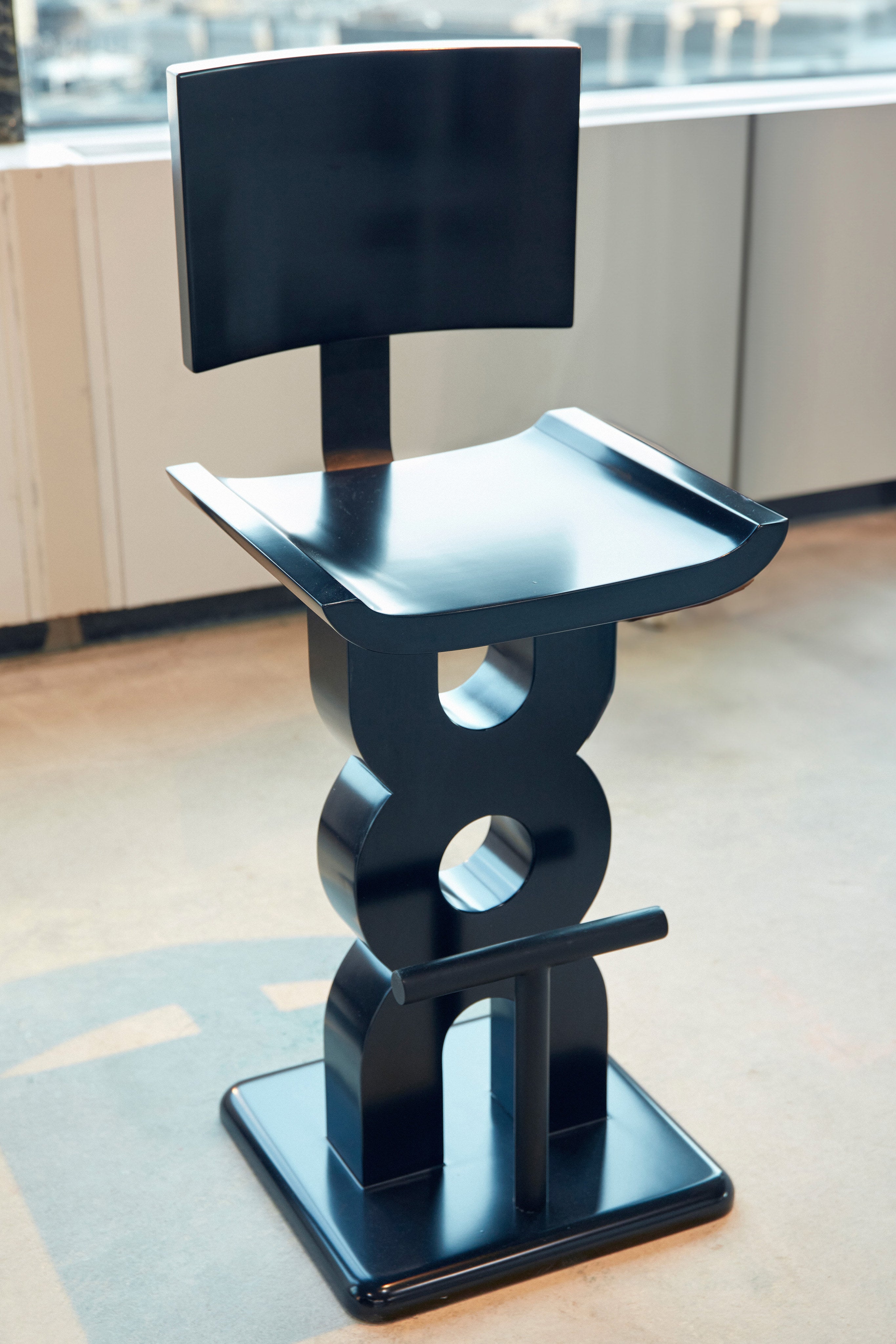 Soro Bar Stool — angled view showing black lacquer finish in modern setting