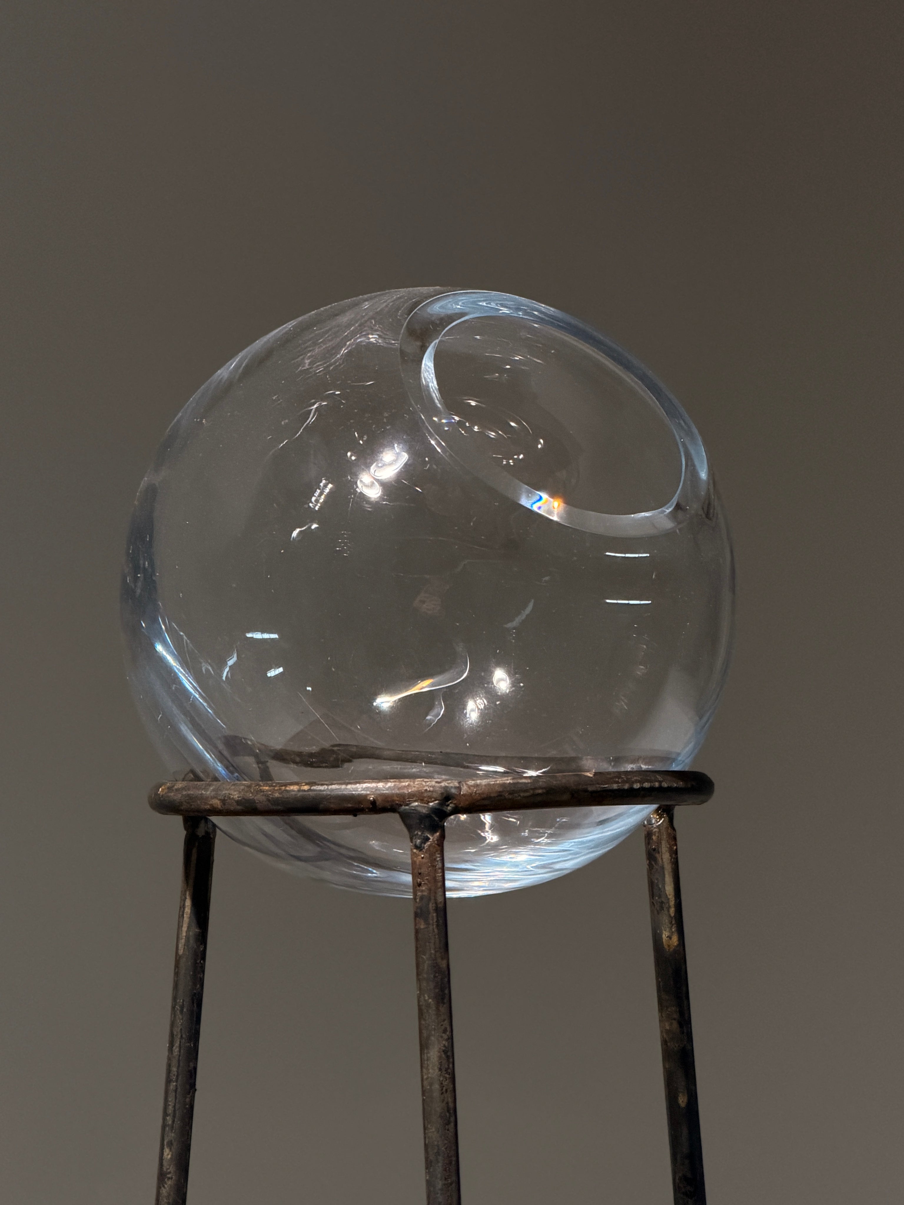 Glass orb vase on wrought iron tripod stand, France, circa 1960 — side angle
