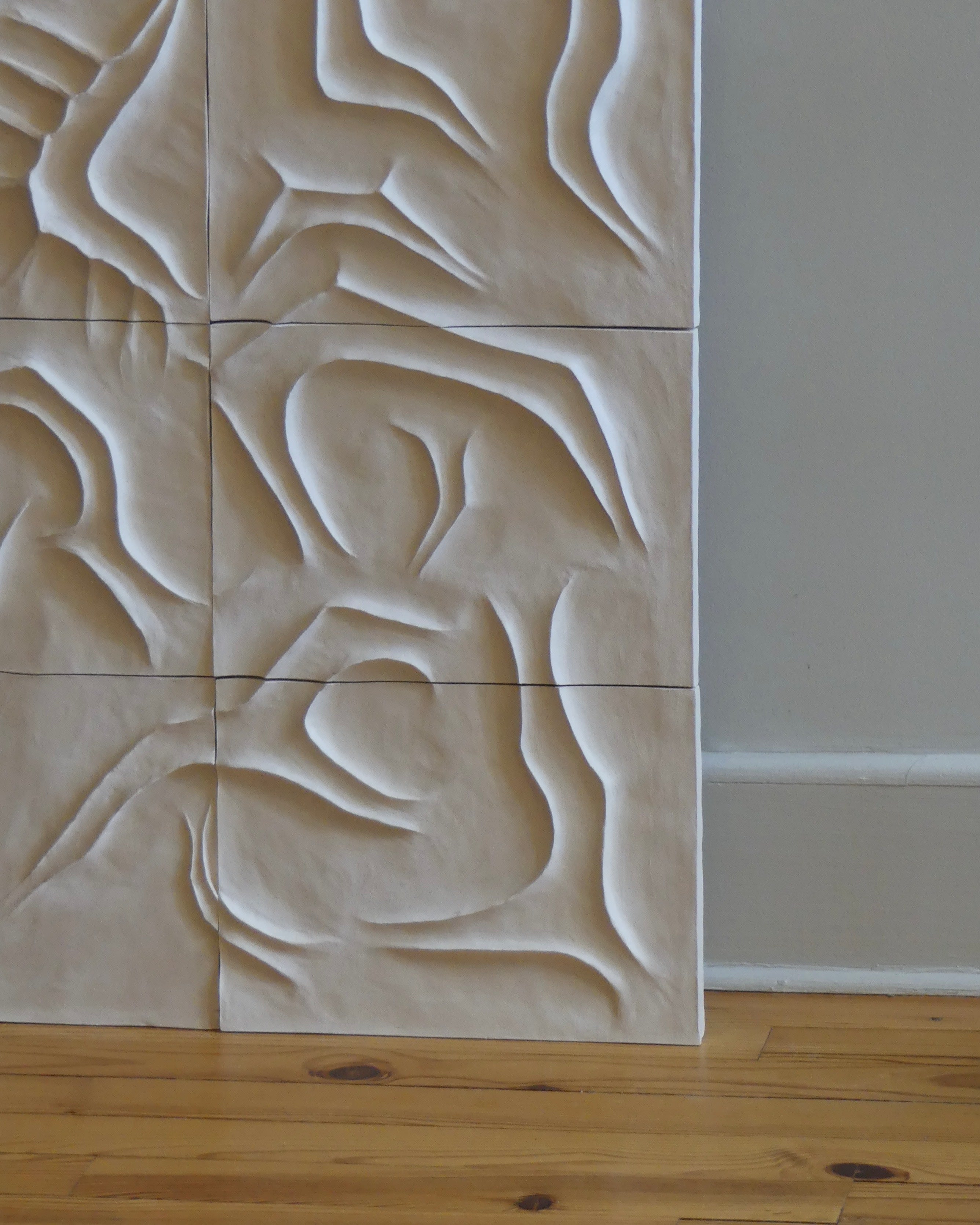 Six Scala Dei Turchi wall sculptures by Franck Scala, featuring white abstract wavy textures, are stacked against a light gray wall near a wooden floor and white baseboard.
