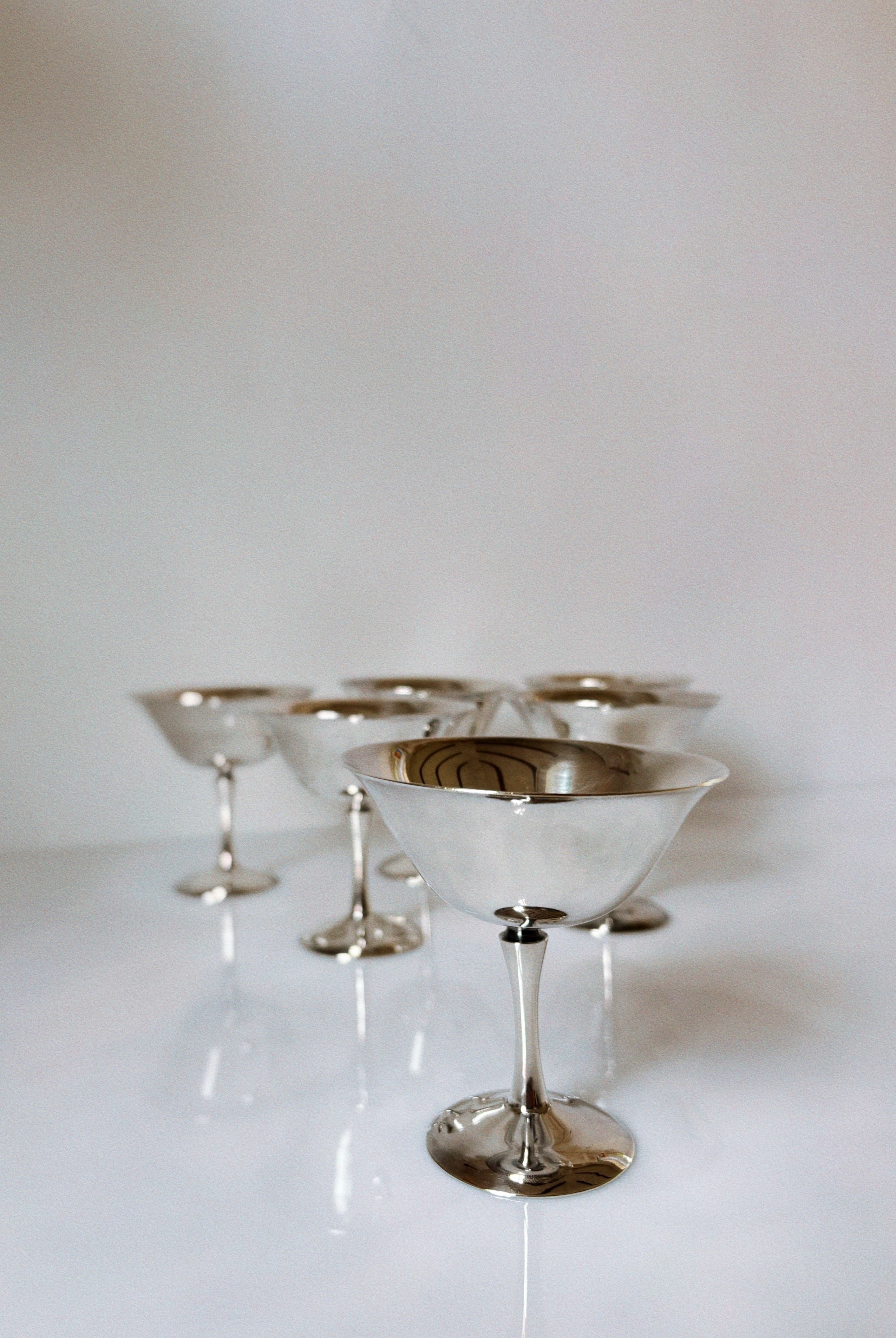 Polish silver plated champagne coupes arranged on white surface